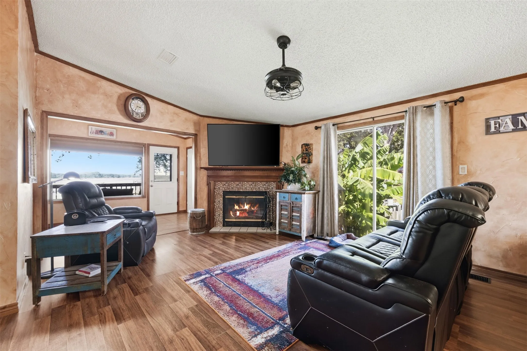 Spacious living area featuring hardwood flooring, a fireplace with decorative surround, built-in cabinetry, and a ceiling-mounted light fixture
