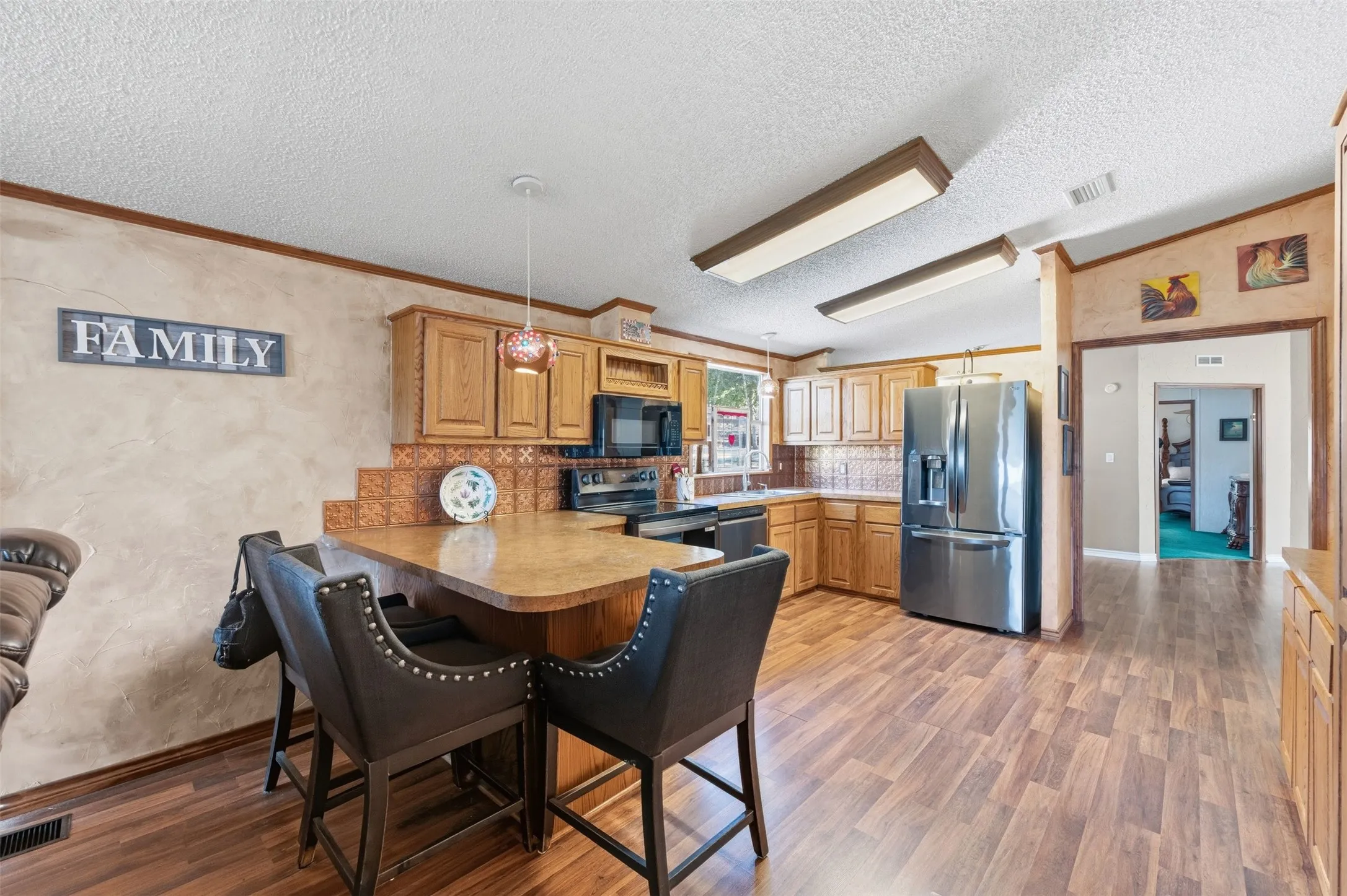Kitchen featuring wood-finish flooring, natural wood cabinetry, stainless steel appliances, and a breakfast bar