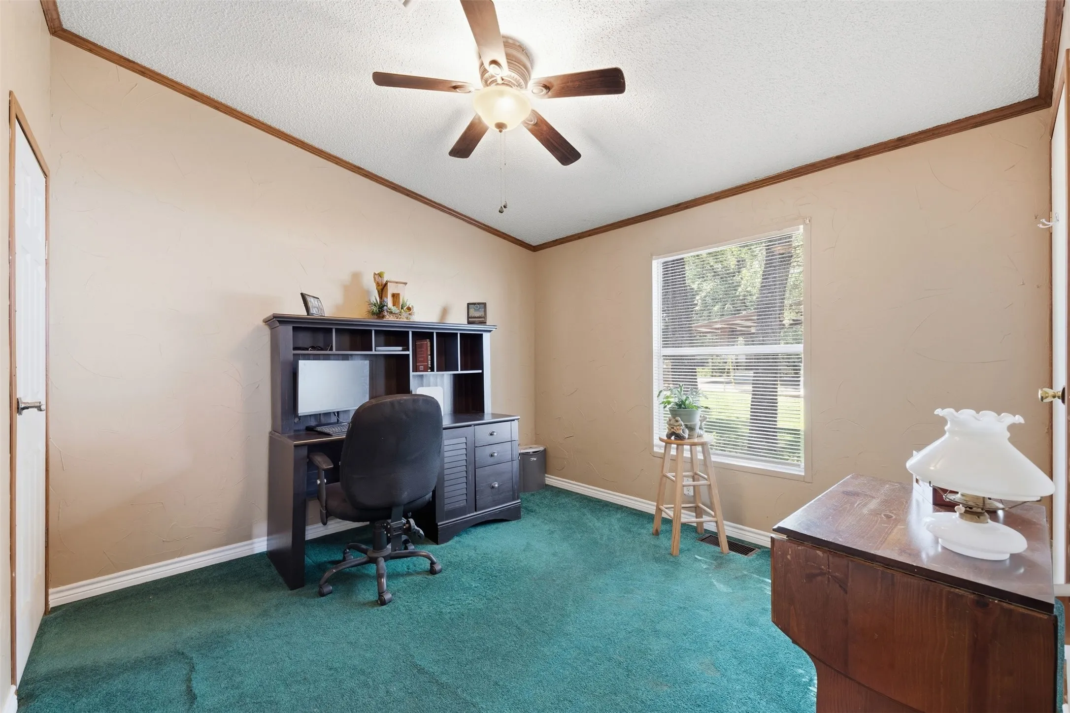 Vaulted ceiling with a ceiling fan, window with horizontal blinds, neutral wall paint, and wood-finish trim