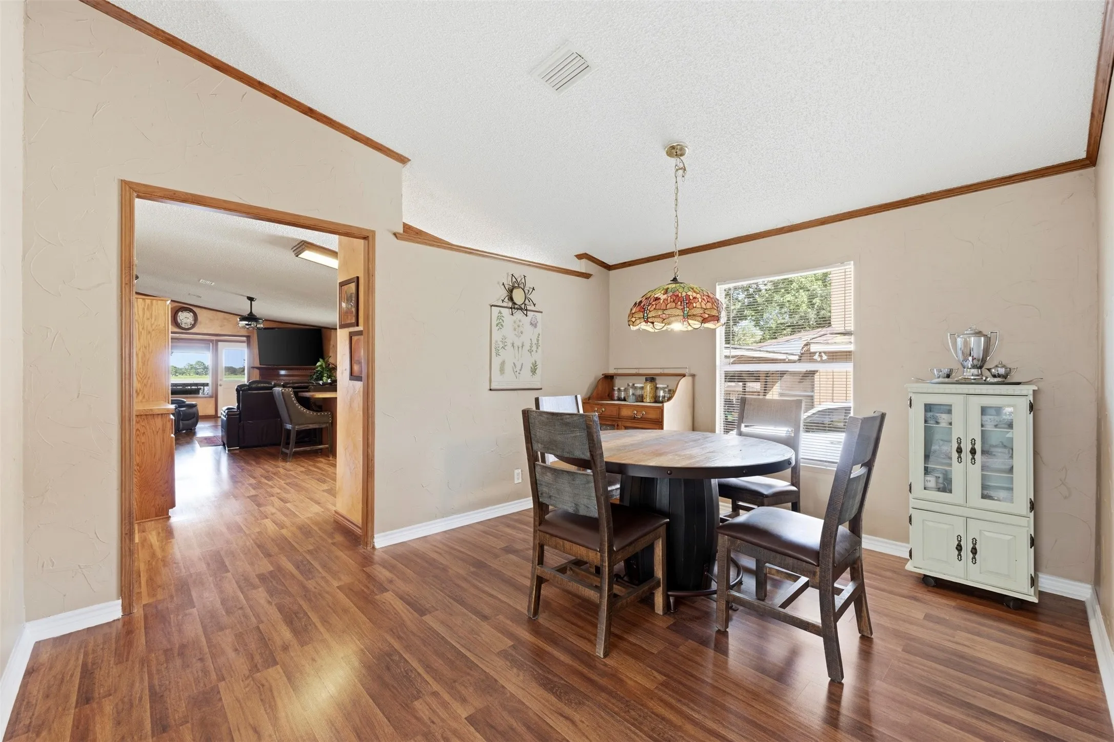 Wood-finish flooring throughout, light-colored walls, wood trim accents, and a window providing natural light