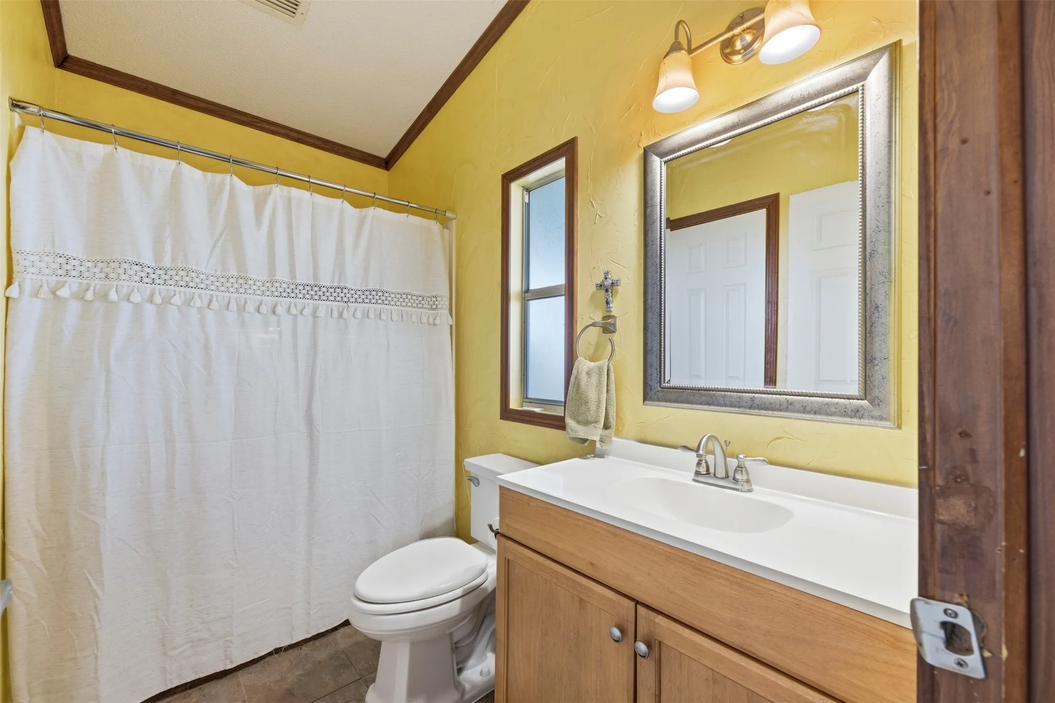 Vanity with integrated sink, two-light fixture, framed mirror, and a window