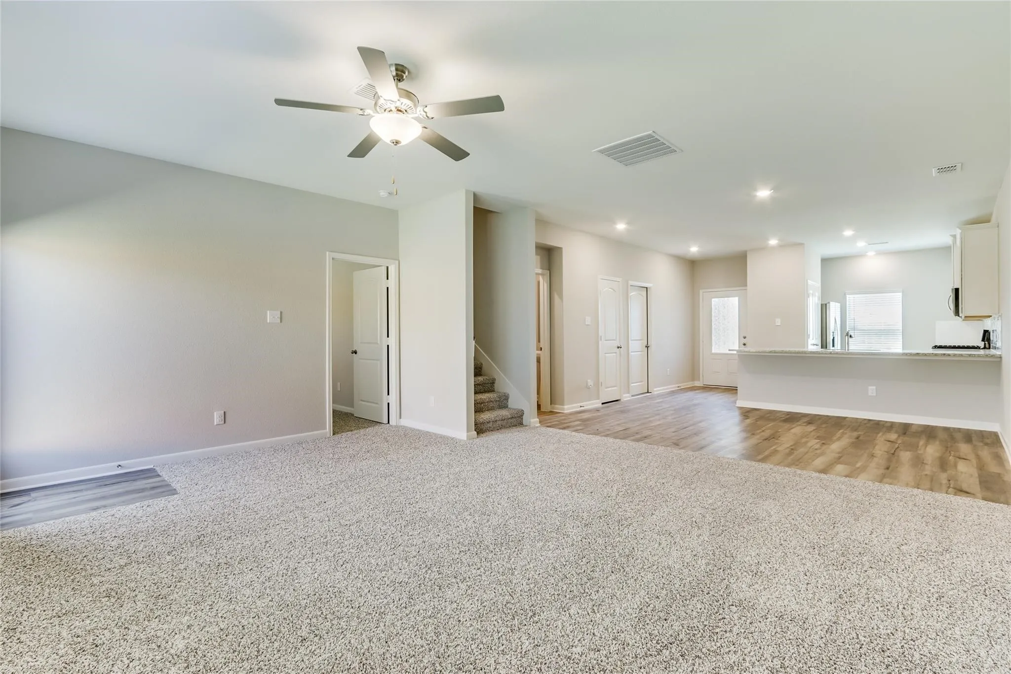 Open concept living area featuring wood-finish flooring, recessed lighting, a ceiling fan, and light-colored carpeting