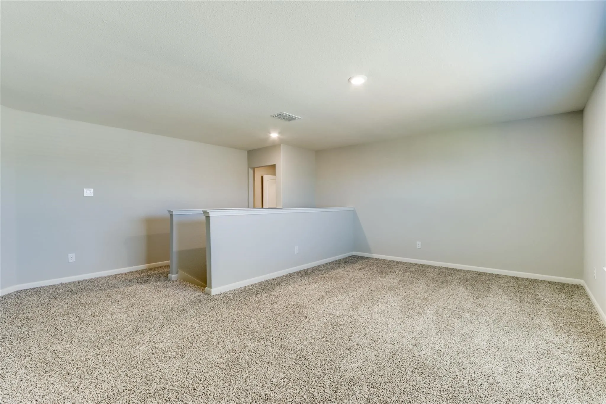 Expansive carpeted area featuring recessed lighting, a neutral color palette, and a low partial wall
