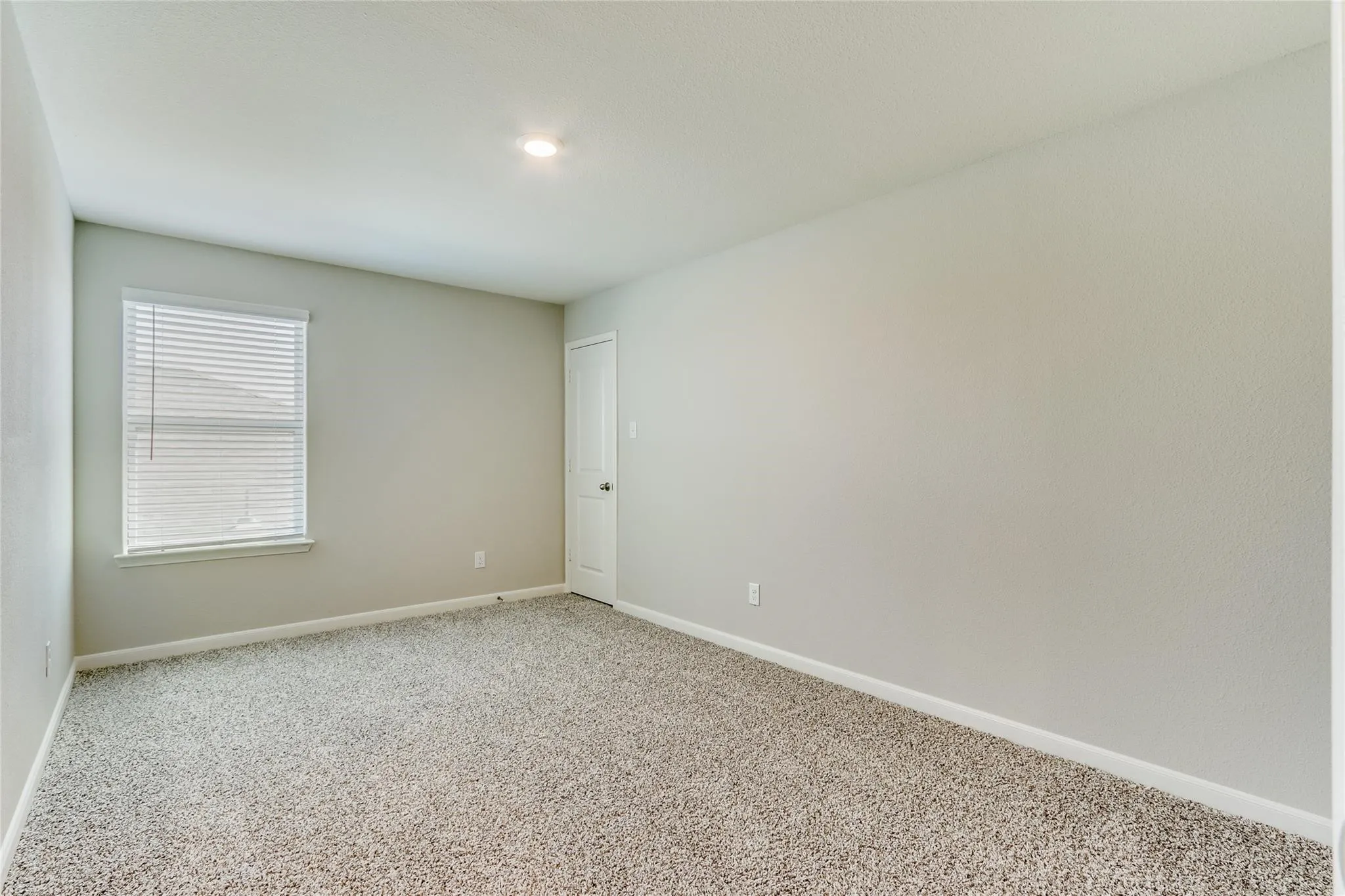 Wall-to-wall carpeting, recessed lighting, and a window with blinds