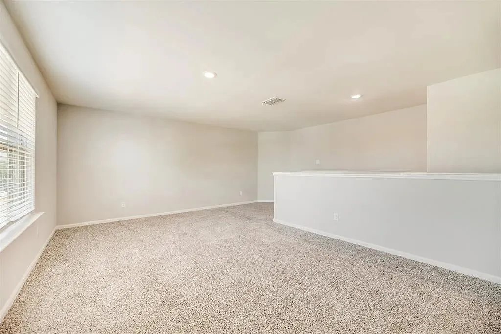 Carpeted flooring, recessed lighting, neutral wall tones, and a window with blinds
