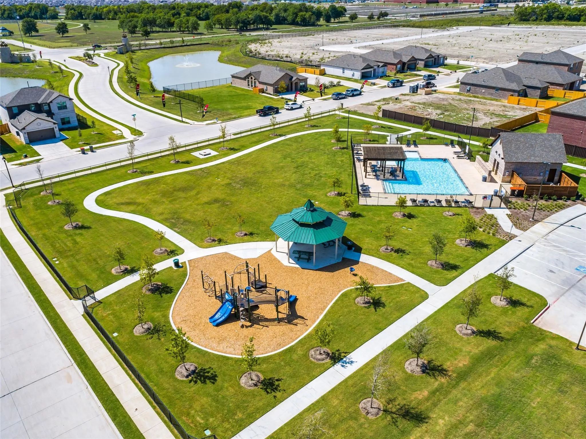 Community green space featuring a playground, gazebo, and swimming pool with a covered lounge area