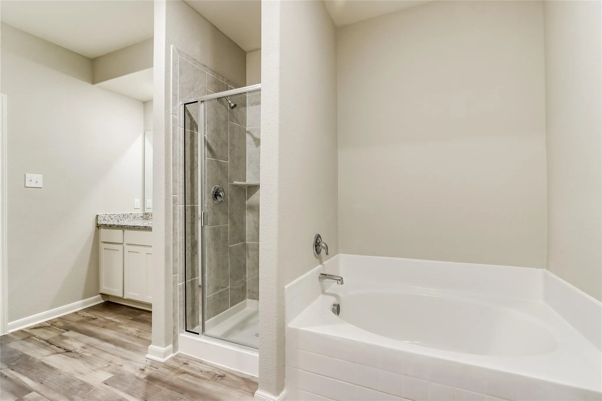 Soaking tub and a separate glass-enclosed shower with tiled walls