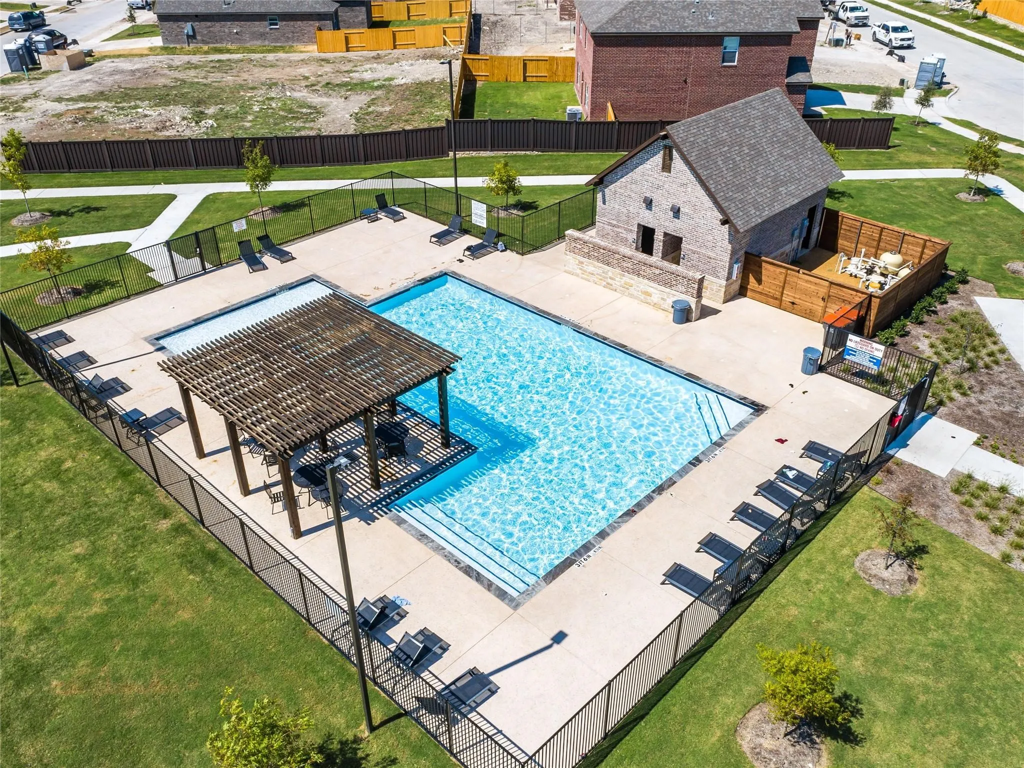 Community pool area with integrated spa, shaded pergola, and surrounding lounge seating