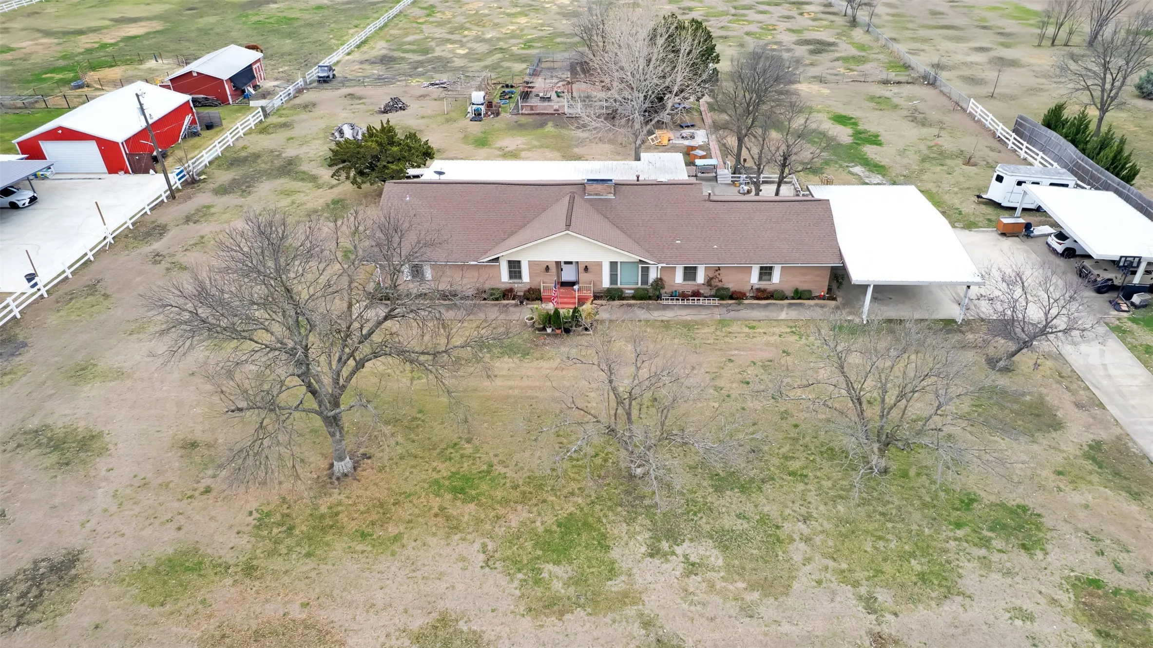 Extensive property featuring a brick exterior residence, two separate carports, and multiple detached red structures