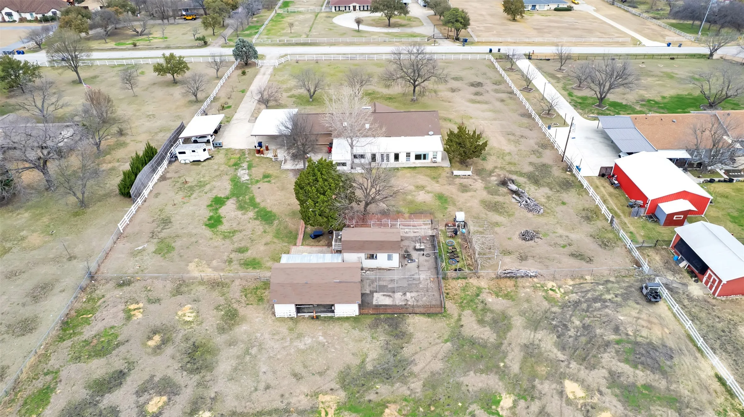 Expansive property featuring multiple structures, including a primary residence with a brown roof, two red barns, and an additional smaller building