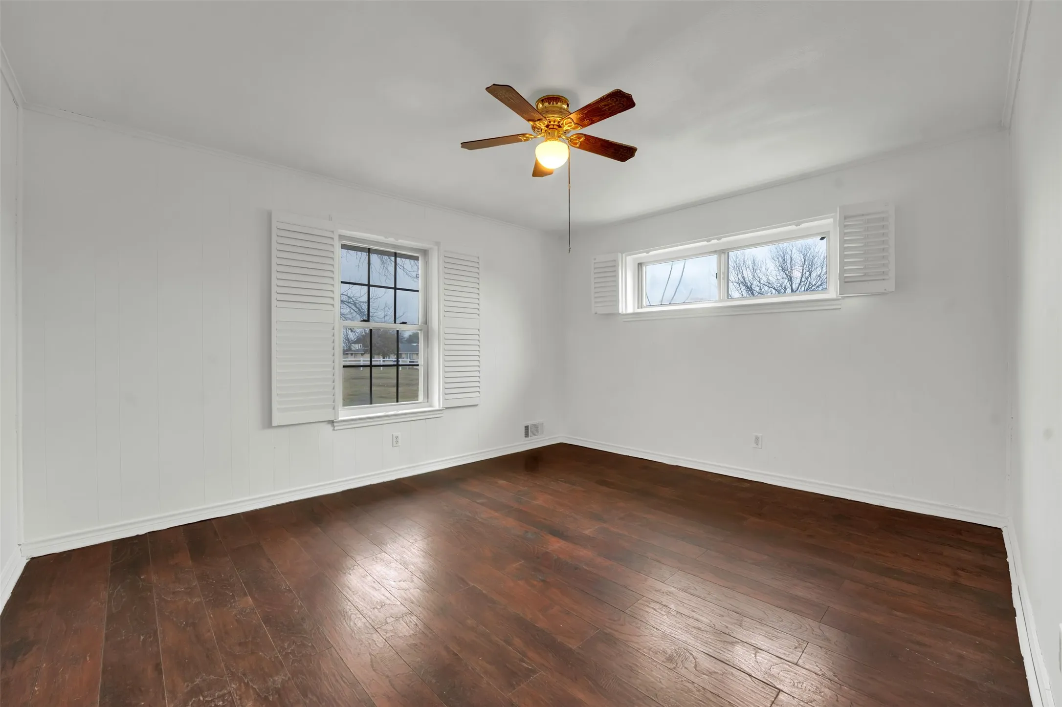 Wood-finish flooring, white walls, and a ceiling fan with integrated lighting