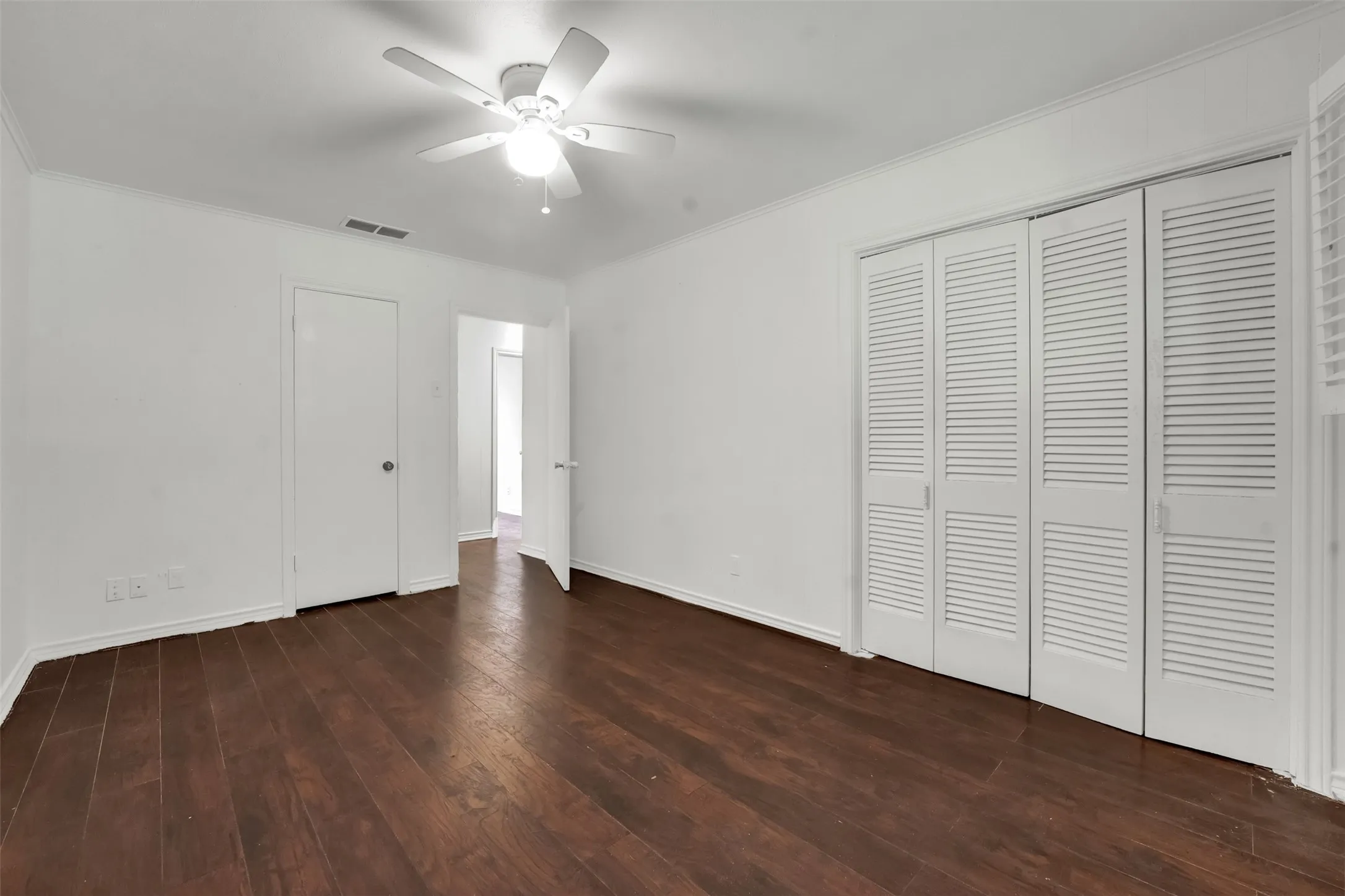 Wood-finish flooring, white walls, louvered bi-fold doors, and a ceiling fan with integrated lighting