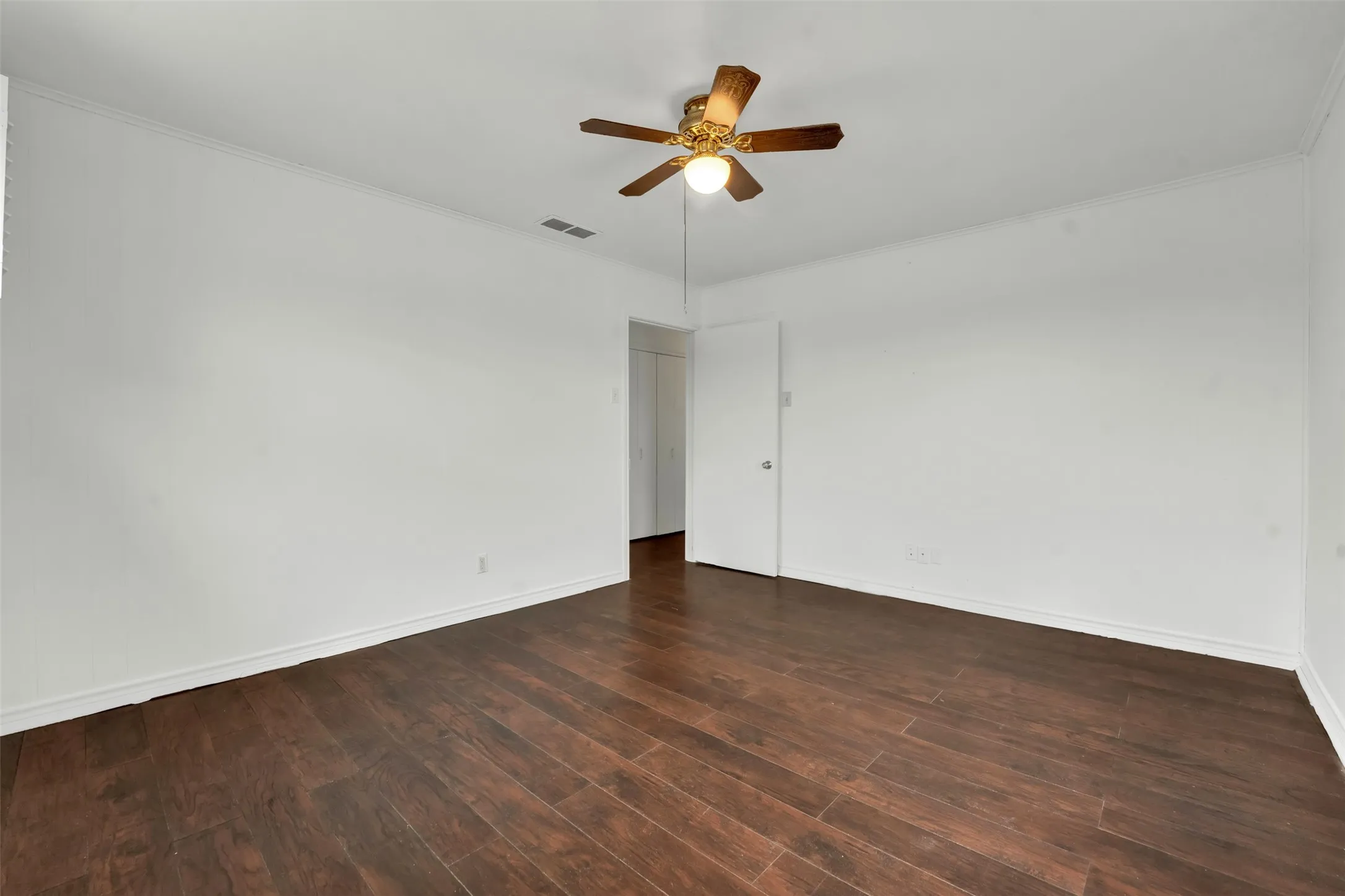Wood-finish flooring, white walls, and a ceiling fan with integrated lighting
