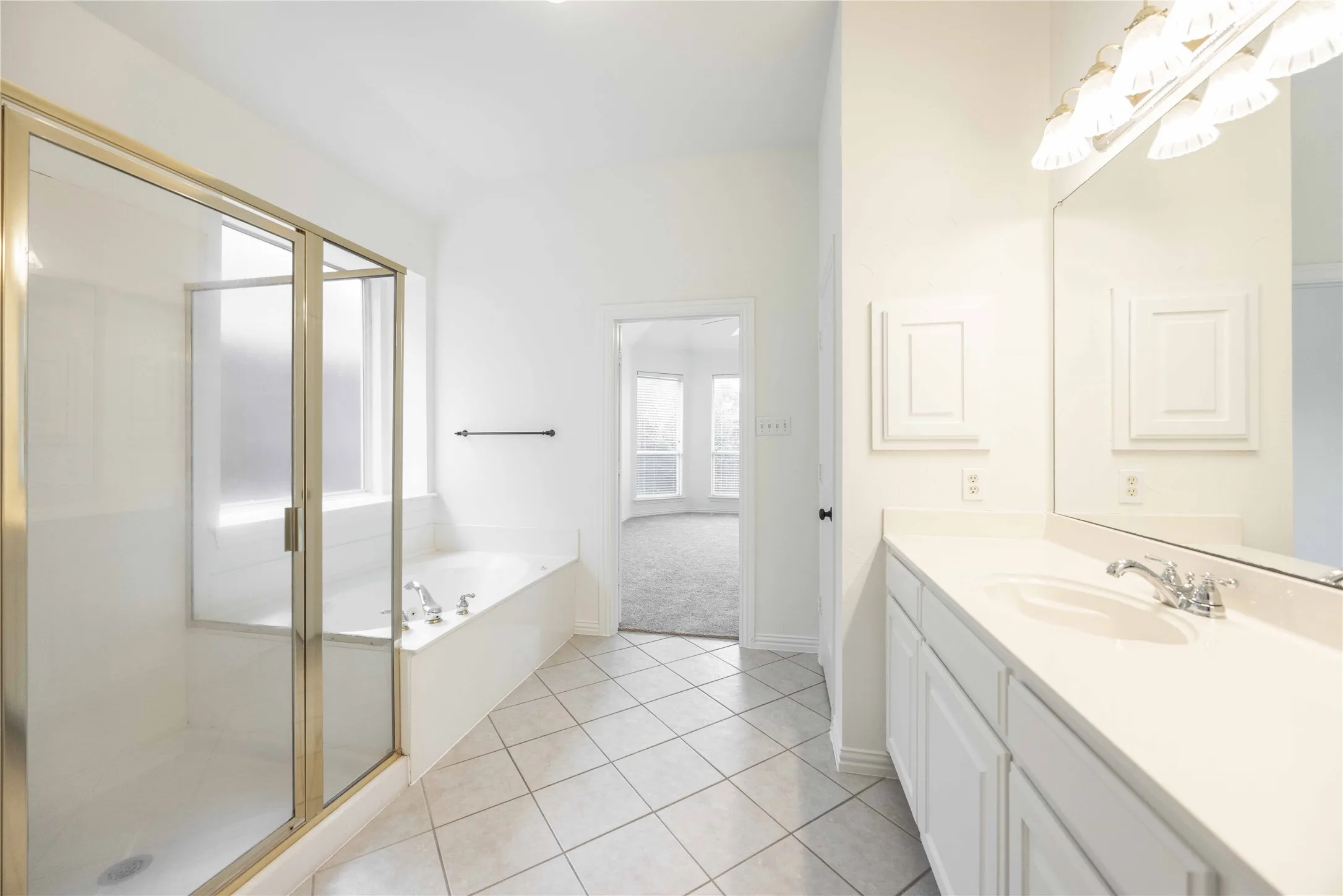 White tiled flooring, vanity with a single basin, built-in storage above the vanity, separate shower, and built-in bathtub