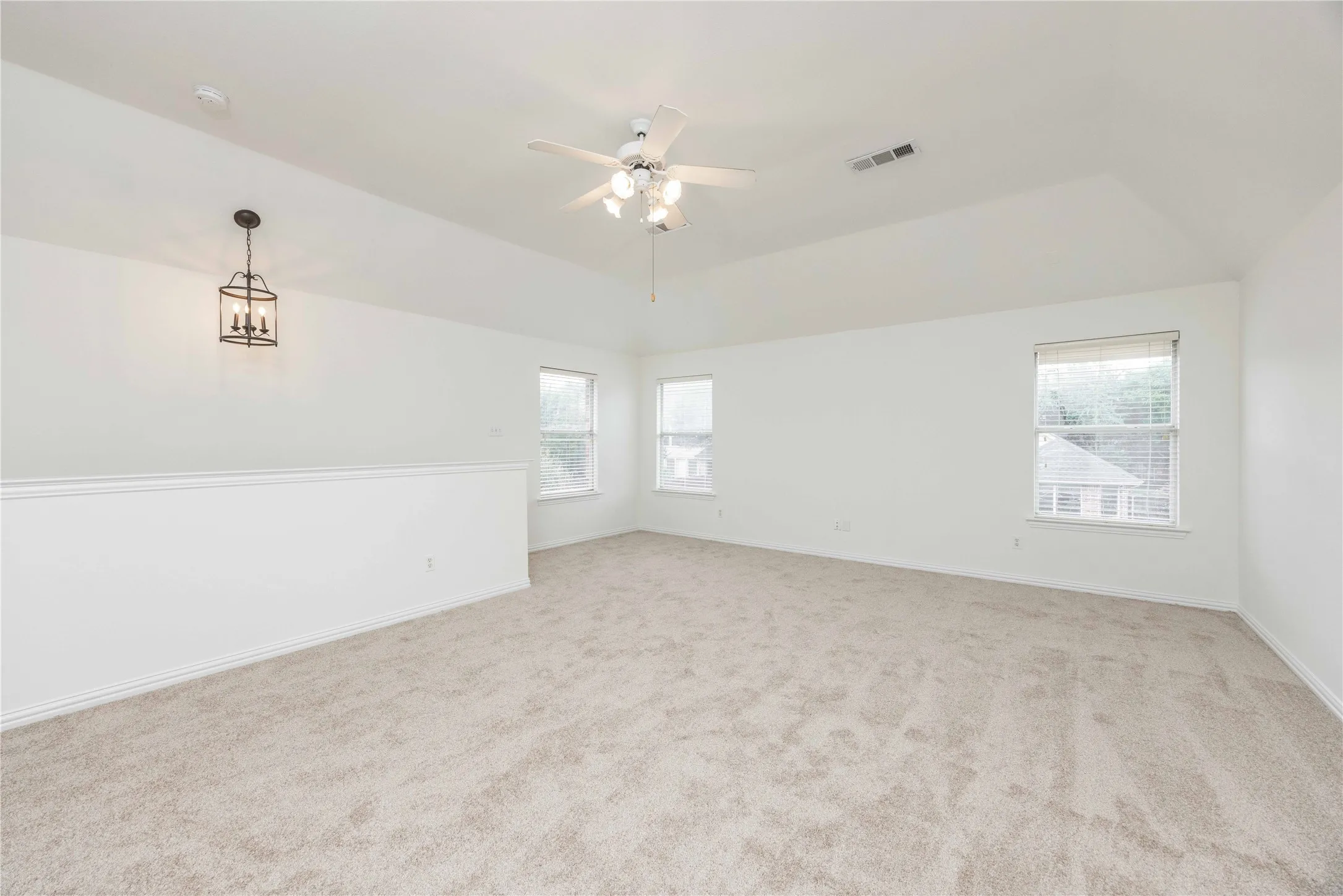 Vaulted ceiling with ceiling fan, recessed windows, and carpet flooring