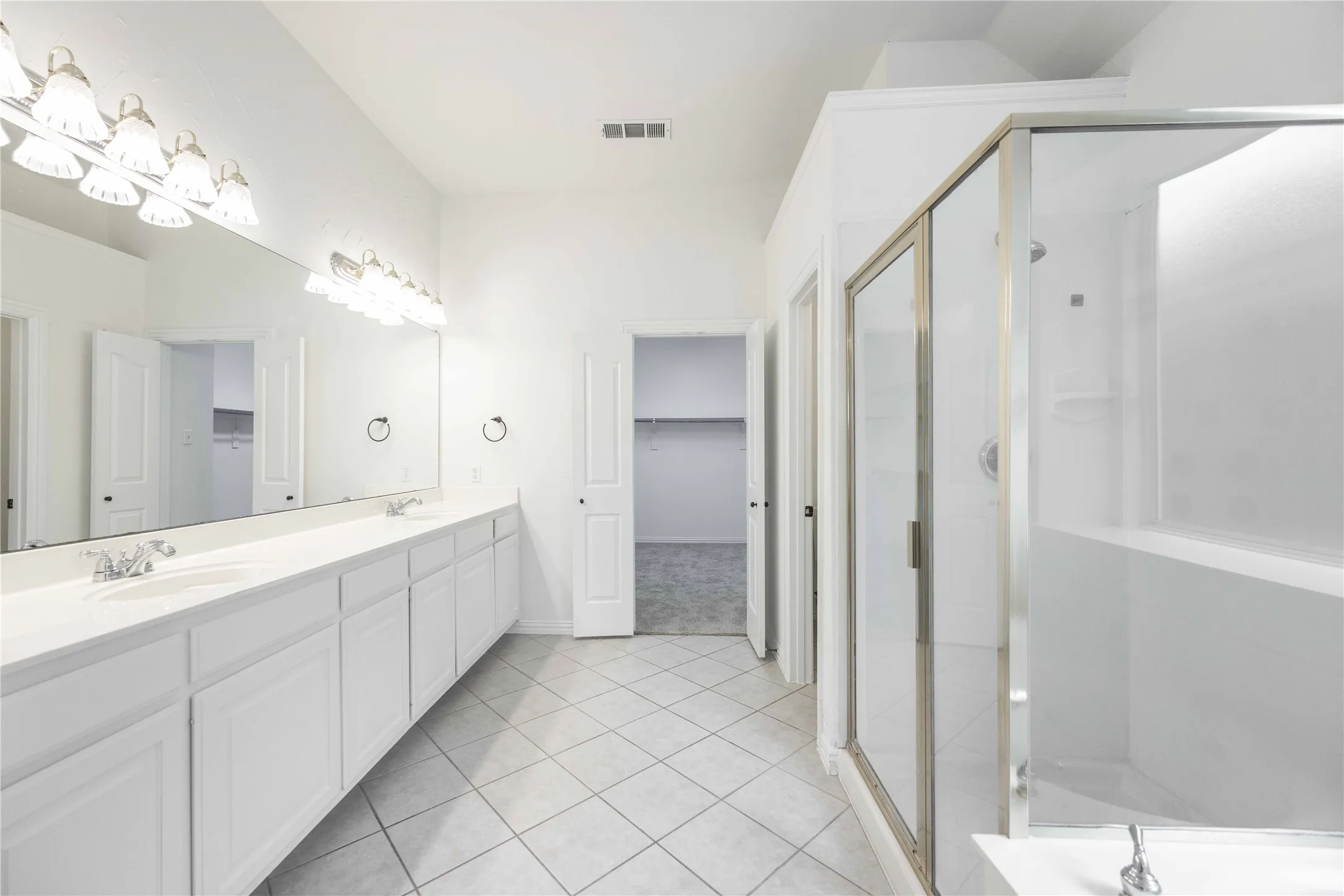 Dual vanity with extensive countertop space, individual sinks, and overhead lighting