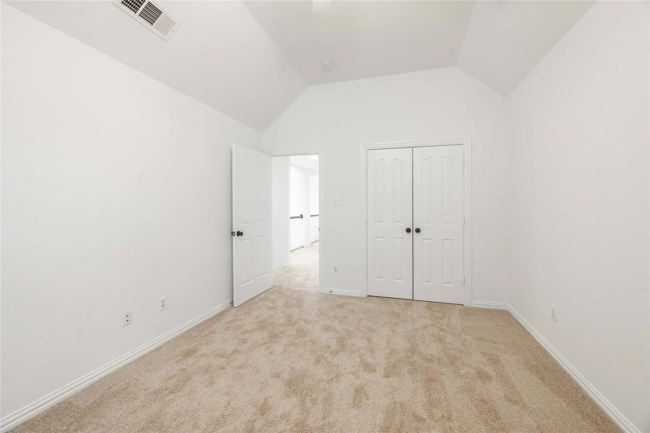Vaulted ceiling, neutral tone walls, carpeted flooring, paneled interior doors, and baseboard molding