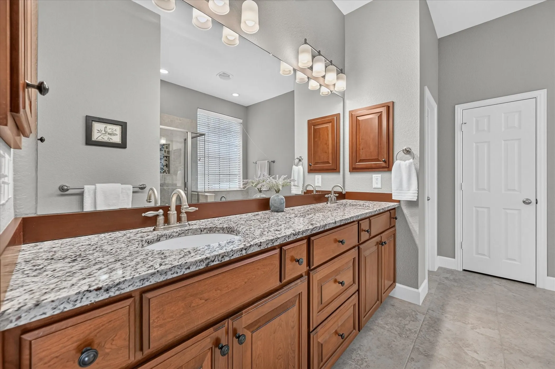 The primary ensuite bath features two undermounted sinks, lovely stone countertops, and two medicine cabinets