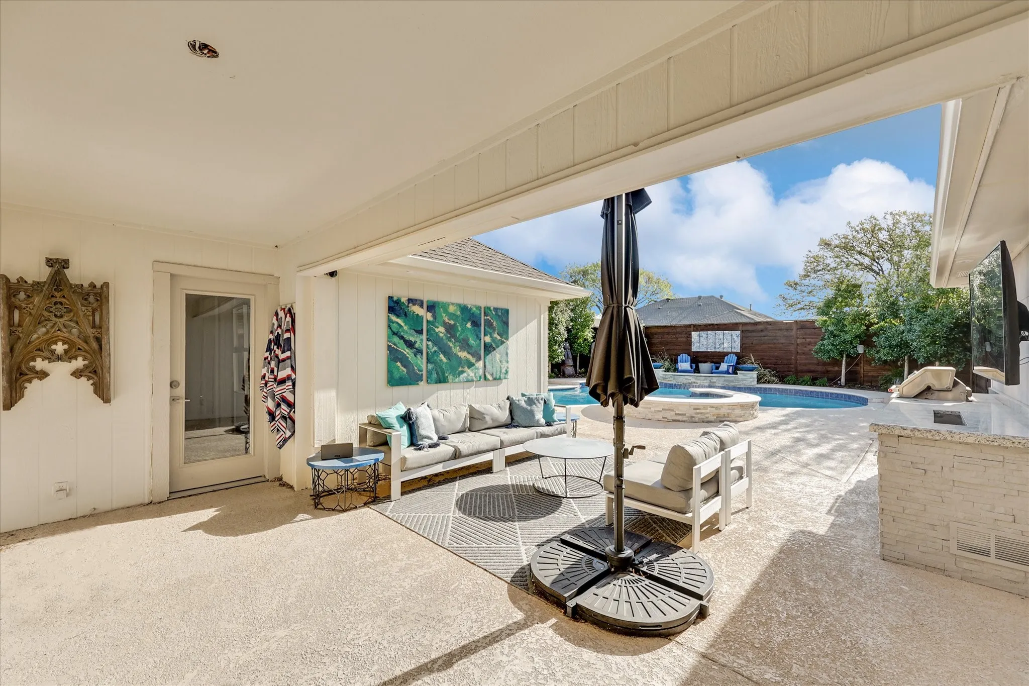 Custom-shaped swimming pool with an integrated spa, surrounded by concrete decking and mature landscaping