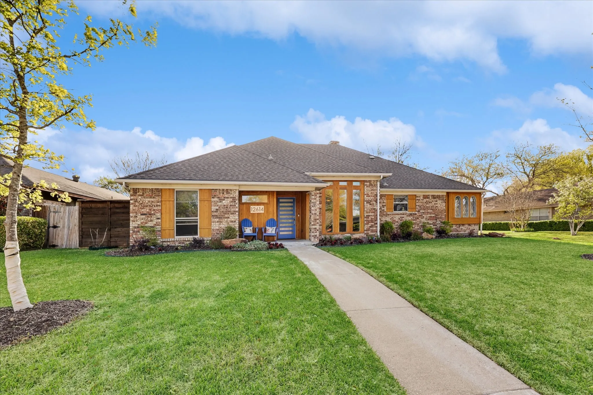 Brick facade with wood-finish accents, gabled roofline, front lawn, and concrete pathway