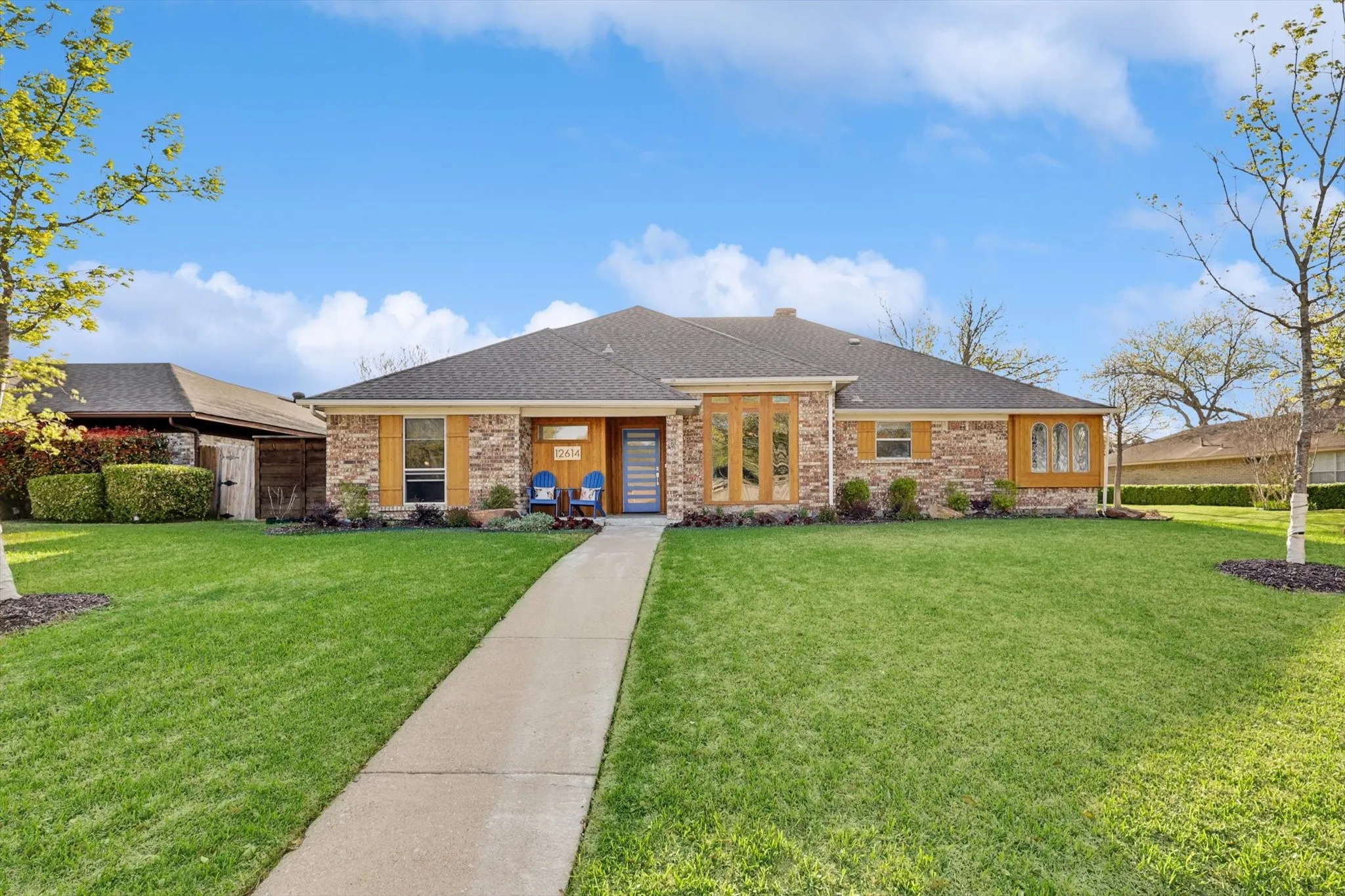 Stone and brick facade with wood-finish accents, gabled roofline, front lawn, and paved walkway