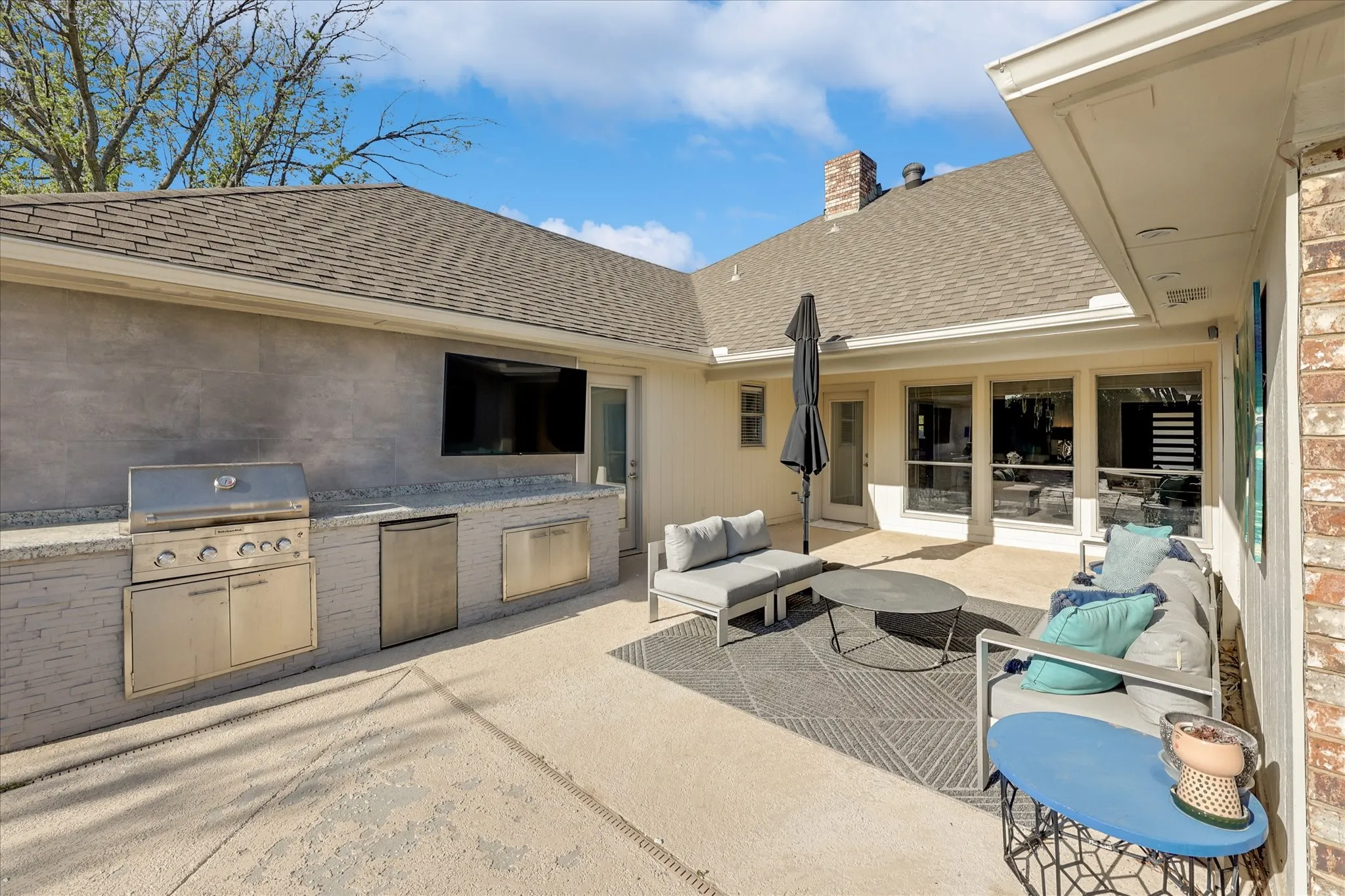 Expansive outdoor living area featuring a covered patio, built-in outdoor kitchen, and a swimming pool with an integrated spa