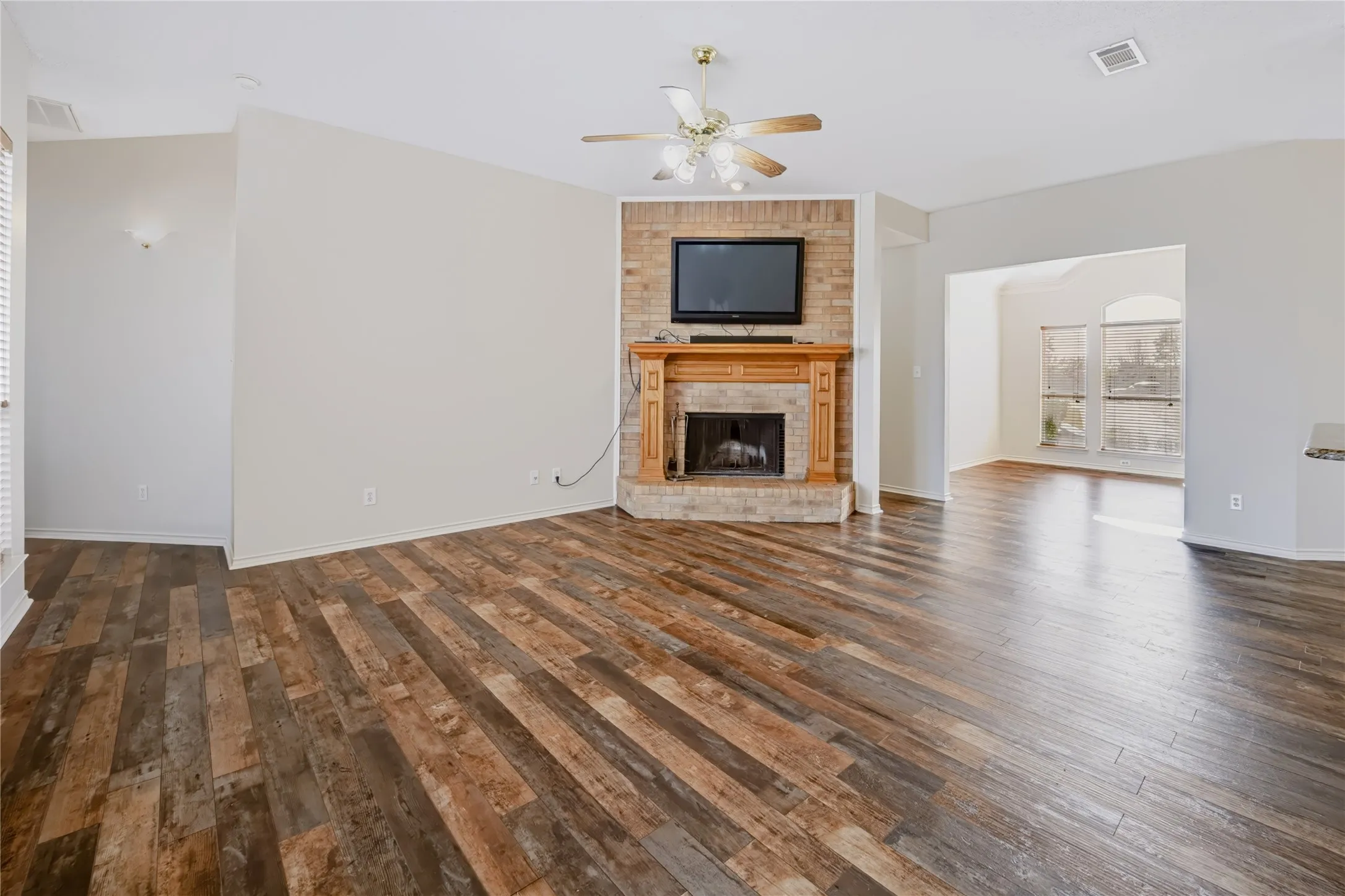 Living area featuring wood-finish flooring, vaulted ceilings, and a floor-to-ceiling brick fireplace with a wood mantel