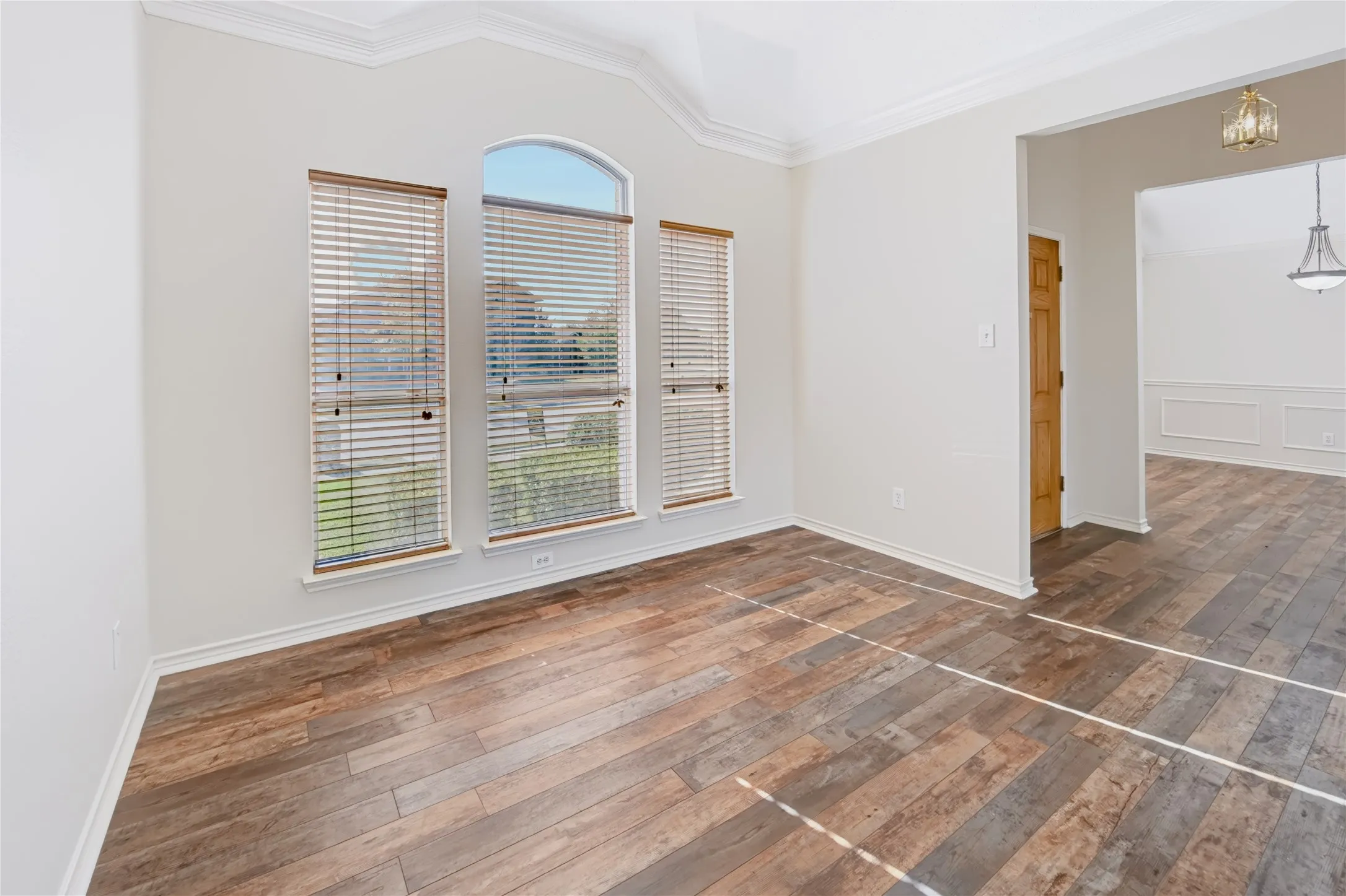 Vaulted ceilings, wood-finish flooring, triple-window configuration with arched top transom, and crown molding