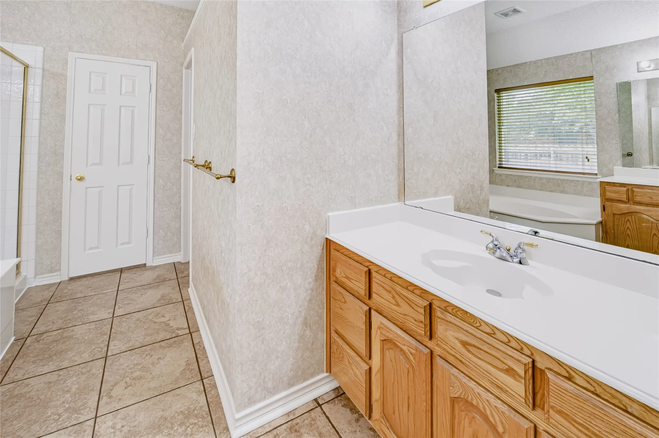 Bathroom featuring ceramic tile flooring, wood cabinetry with a solid surface countertop, integrated sink, and full-width vanity mirror