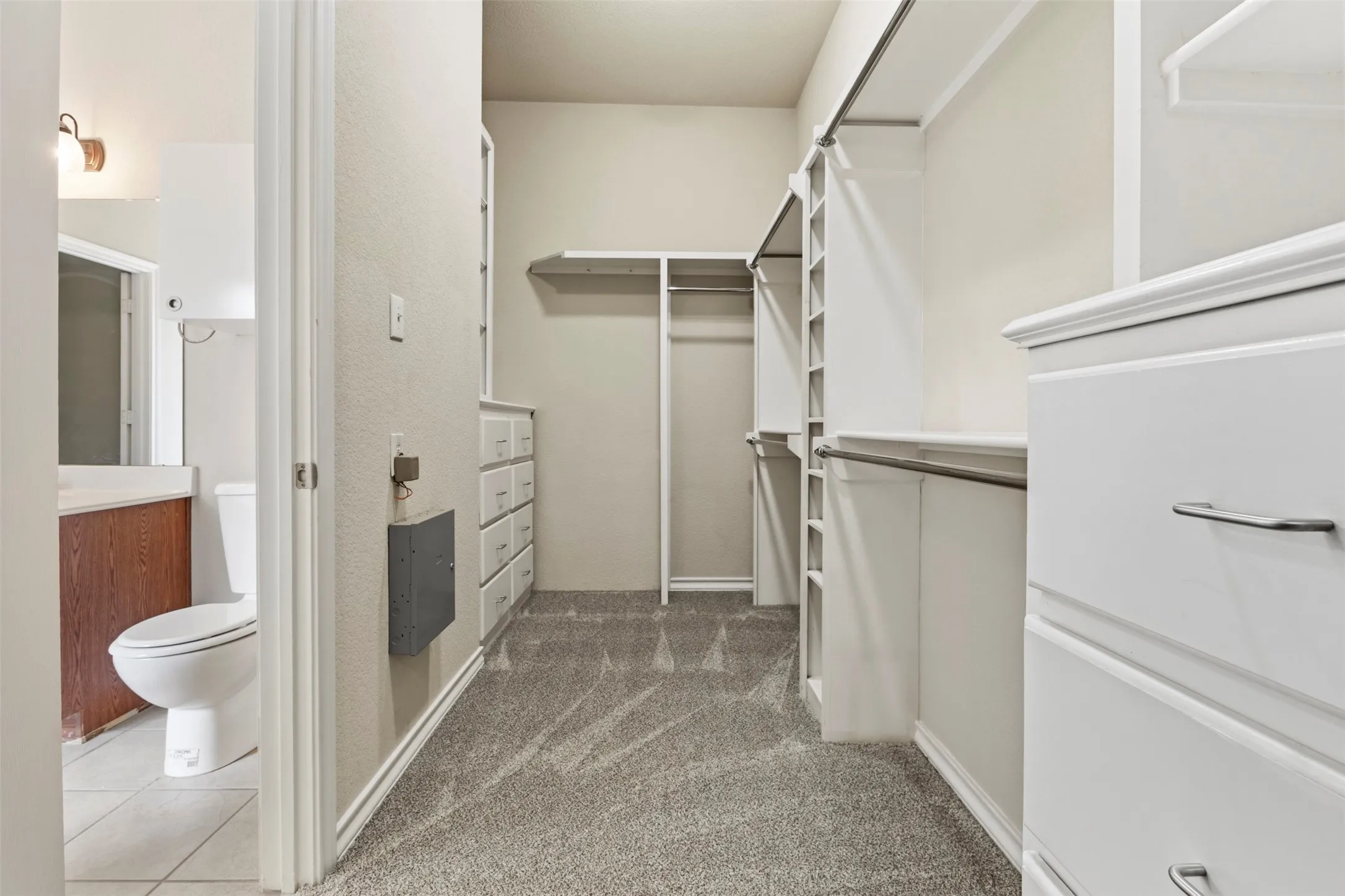 Custom primary closet with built-in dressers and shoe racks allow for plenty of storage space without needing extra bedroom furniture.