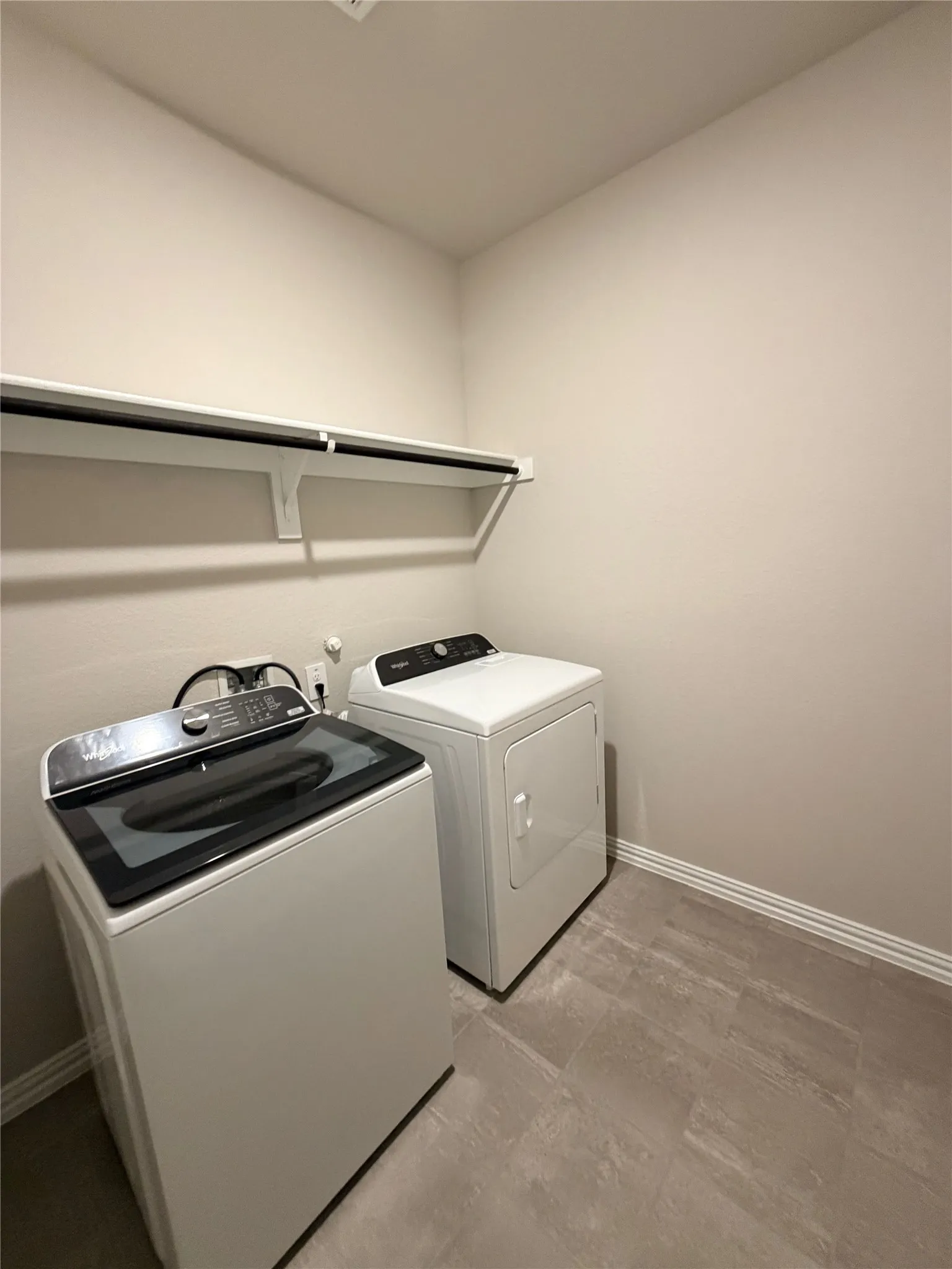 Built-in shelving with hanging rod, durable floor tiling, and a dedicated laundry area