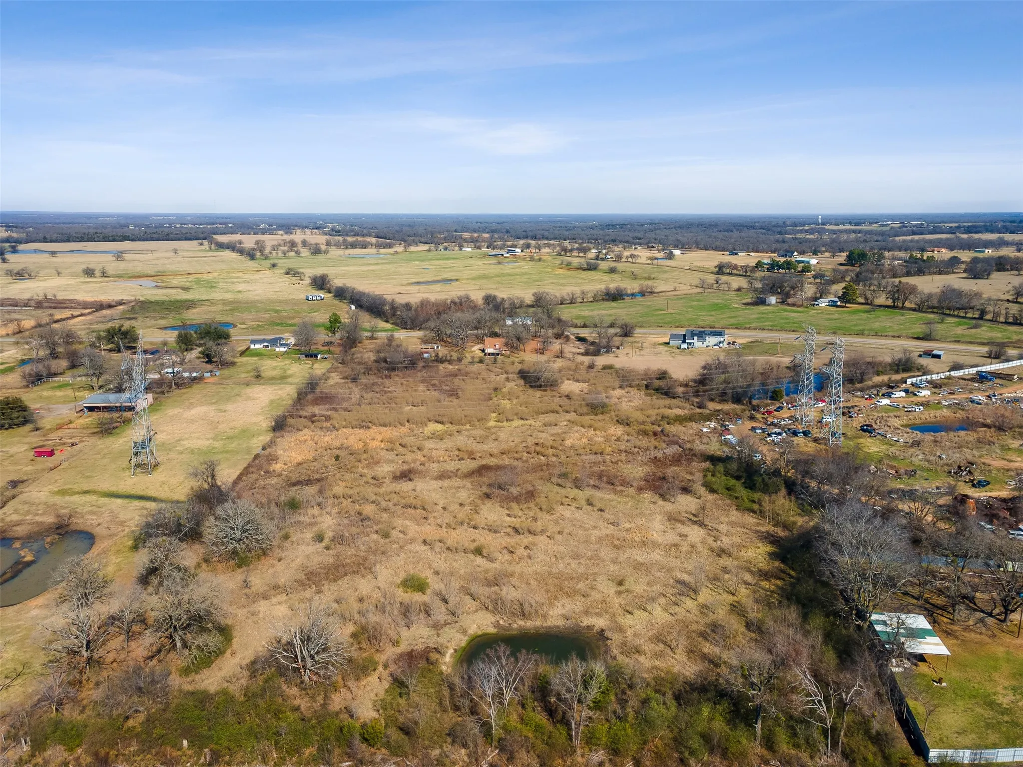 Expansive land parcel featuring open fields, scattered trees, and two visible ponds
