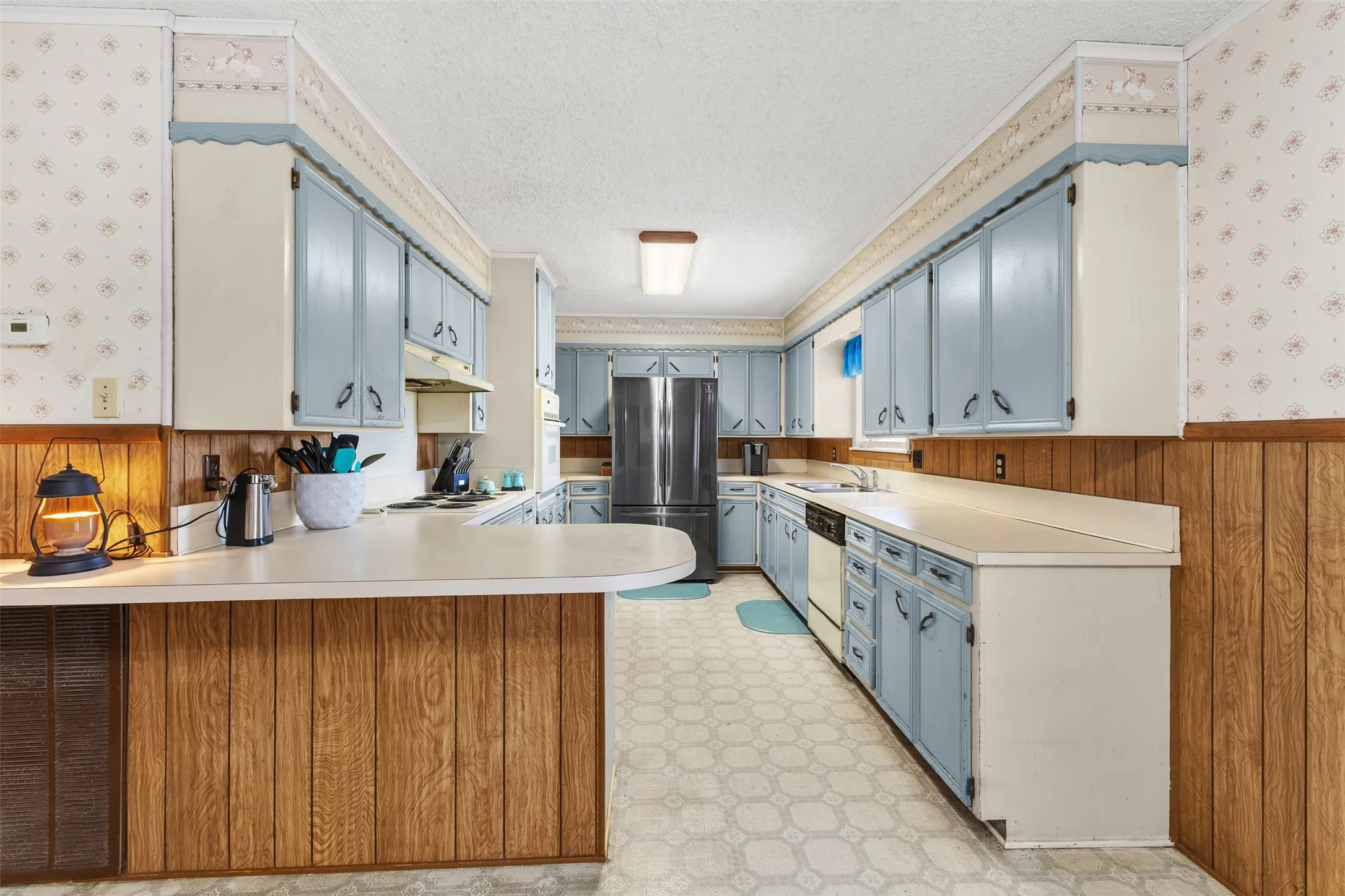 U-shaped kitchen layout with extensive cabinetry, a double basin sink, and wood-finish paneling