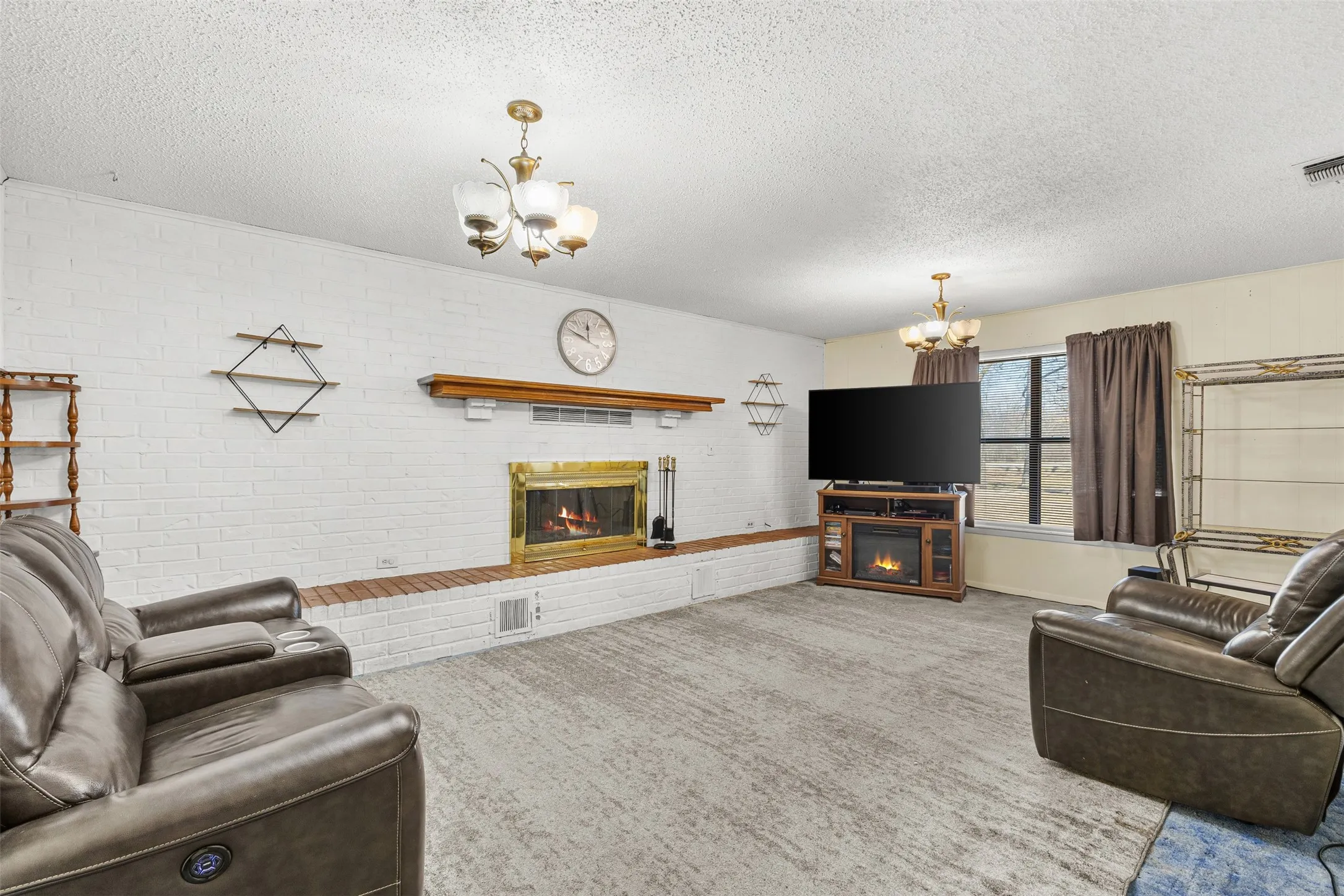 White painted brick fireplace with brass firebox and wood mantel