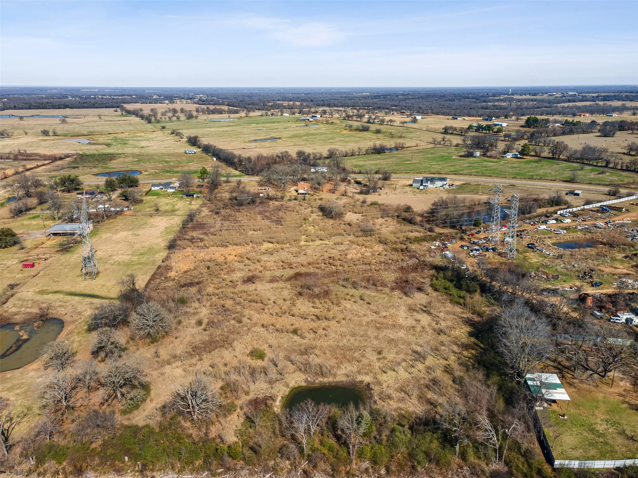 Expansive land parcel featuring open fields, scattered mature trees, and multiple small ponds