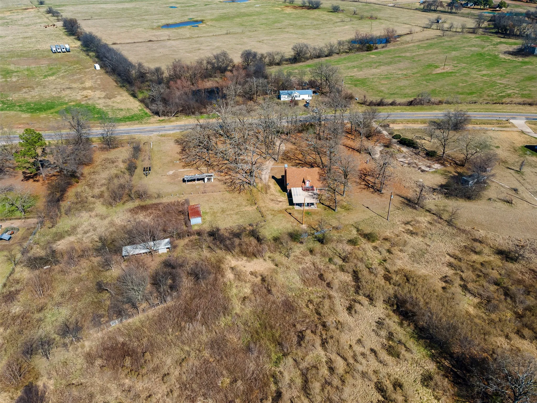 Property featuring a red roof structure, mature trees, and expansive open land