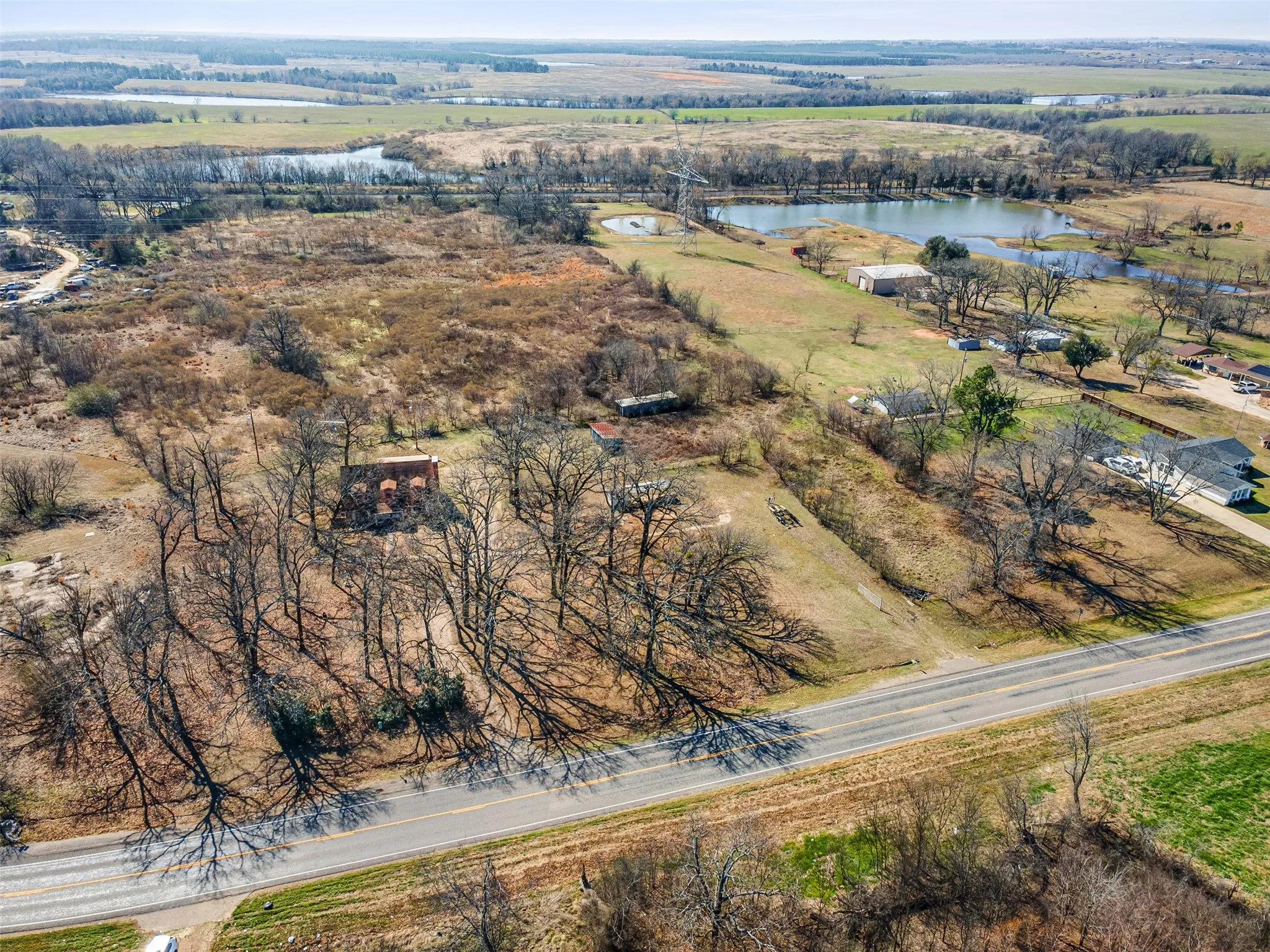 Expansive land parcel with direct road frontage, mature trees, and a distant water feature