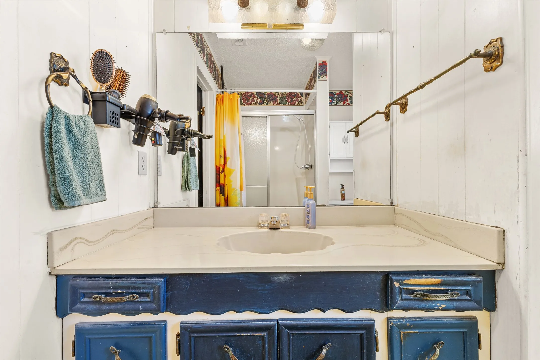 Vanity with an integrated sink, blue-painted cabinetry, wall-mounted mirror, and overhead light fixture