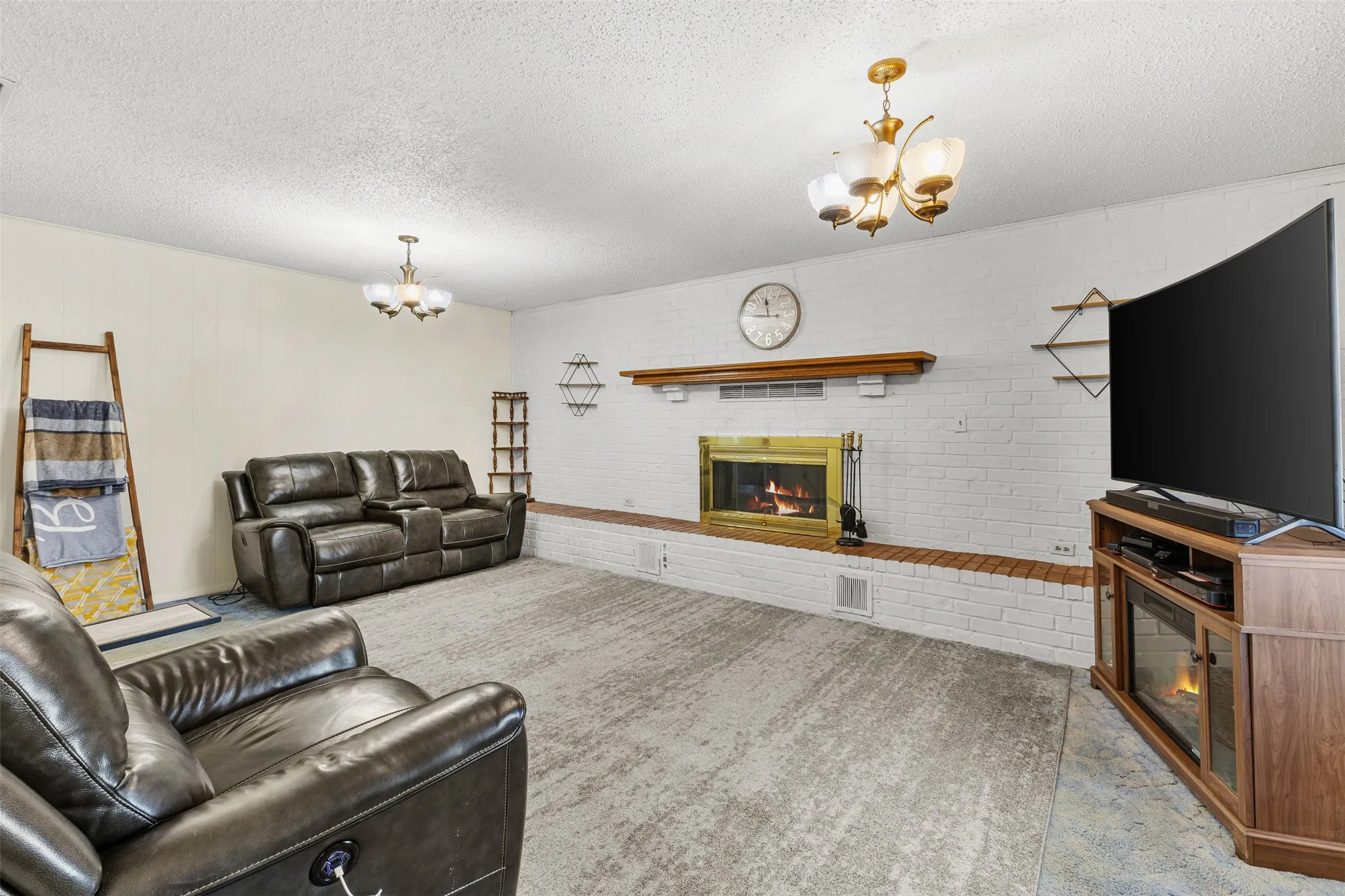 White-painted brick fireplace with a brass firebox and wood mantel