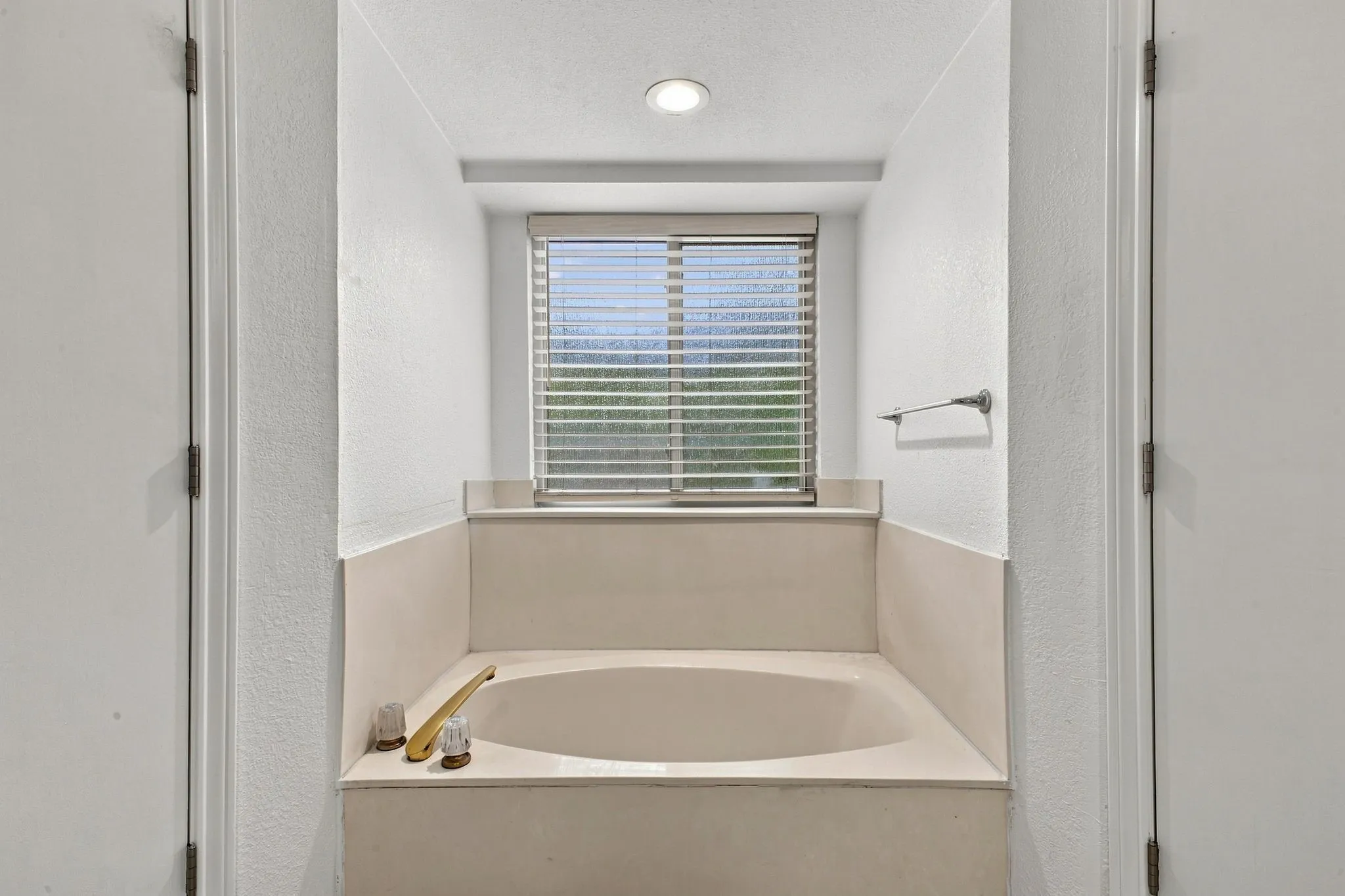 Recessed soaking tub with surrounding ledge, integrated window, and recessed ceiling lighting
