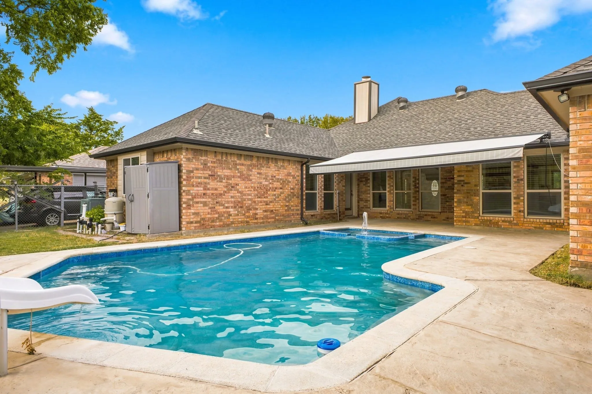 In-ground swimming pool with integrated spa and fountain feature