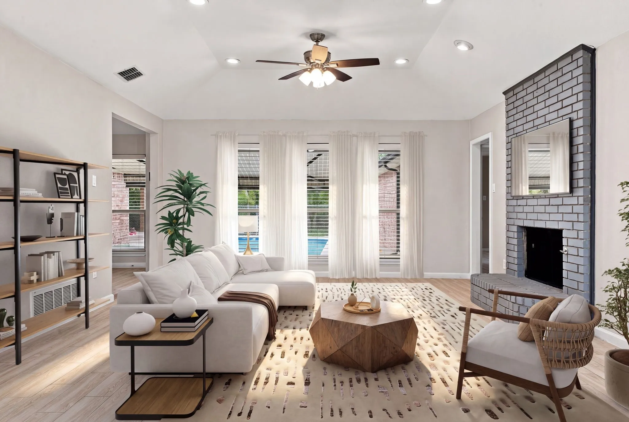 Vaulted ceiling with recessed lighting and ceiling fan, wood-finish flooring, three large windows, brick fireplace, and built-in shelving