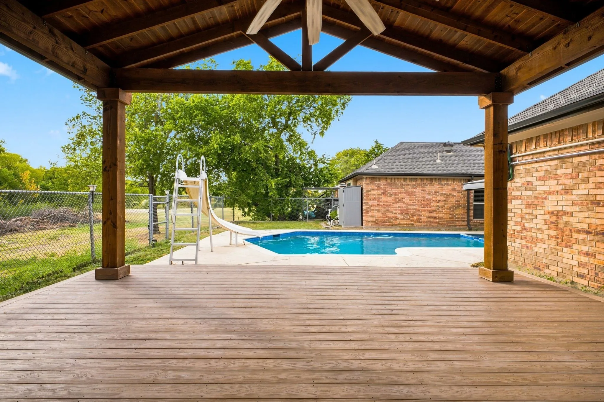 Expansive covered patio featuring a wood ceiling, wood-finish decking, and a ceiling fan