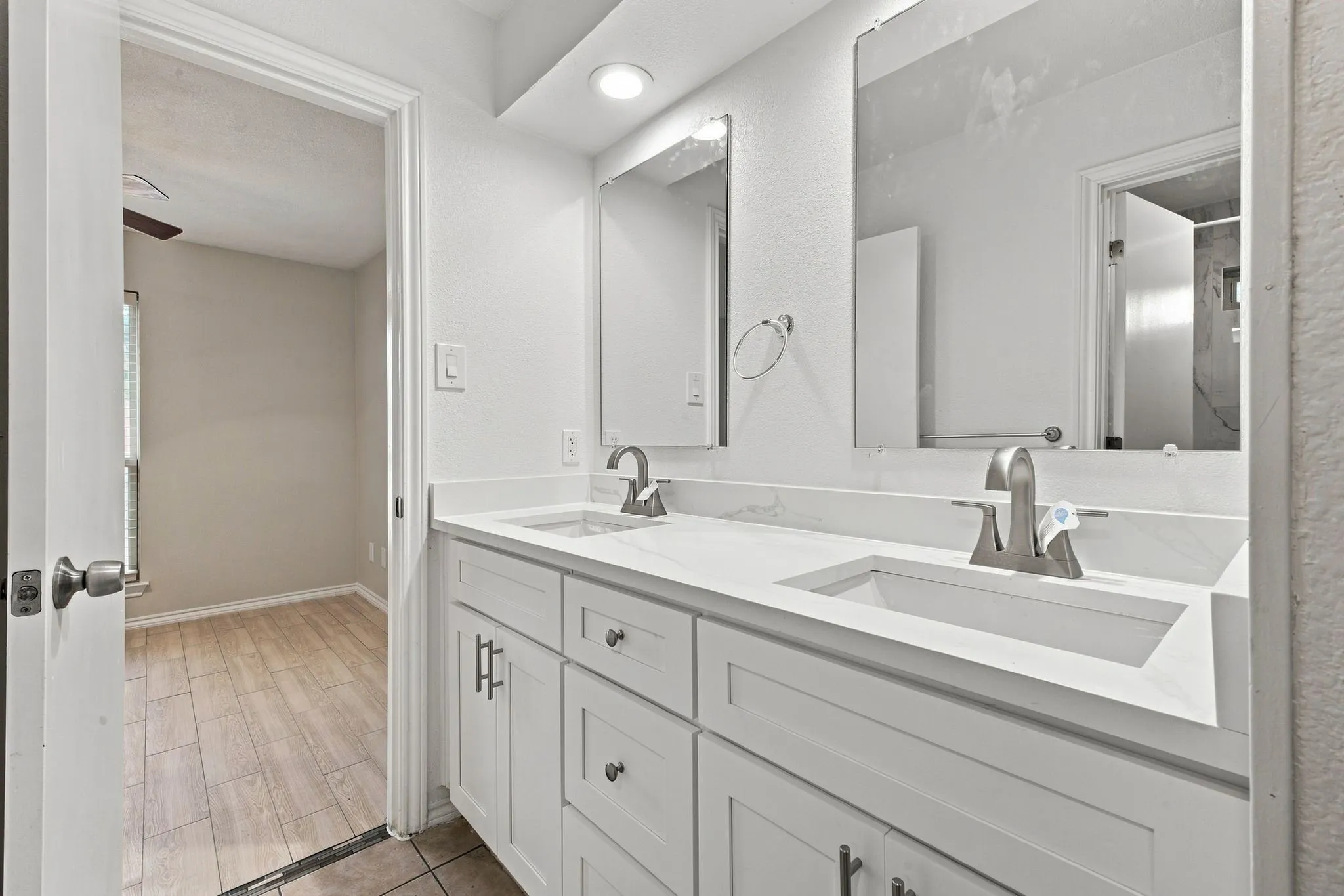 Dual vanity with white cabinetry, integrated sinks, brushed nickel faucets, and frameless mirrors