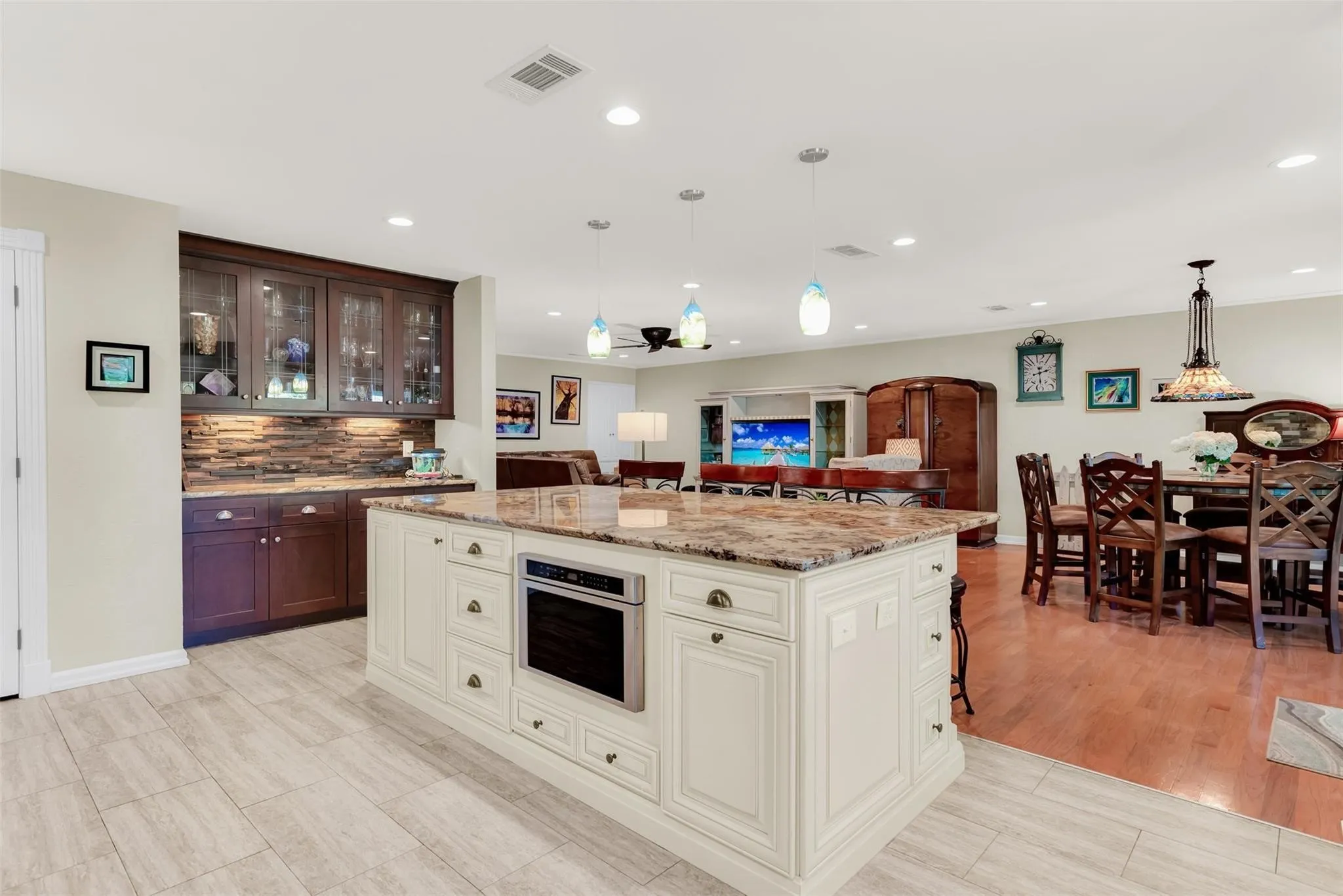 Kitchen island with integrated microwave, pendant lighting, and light-toned tile flooring