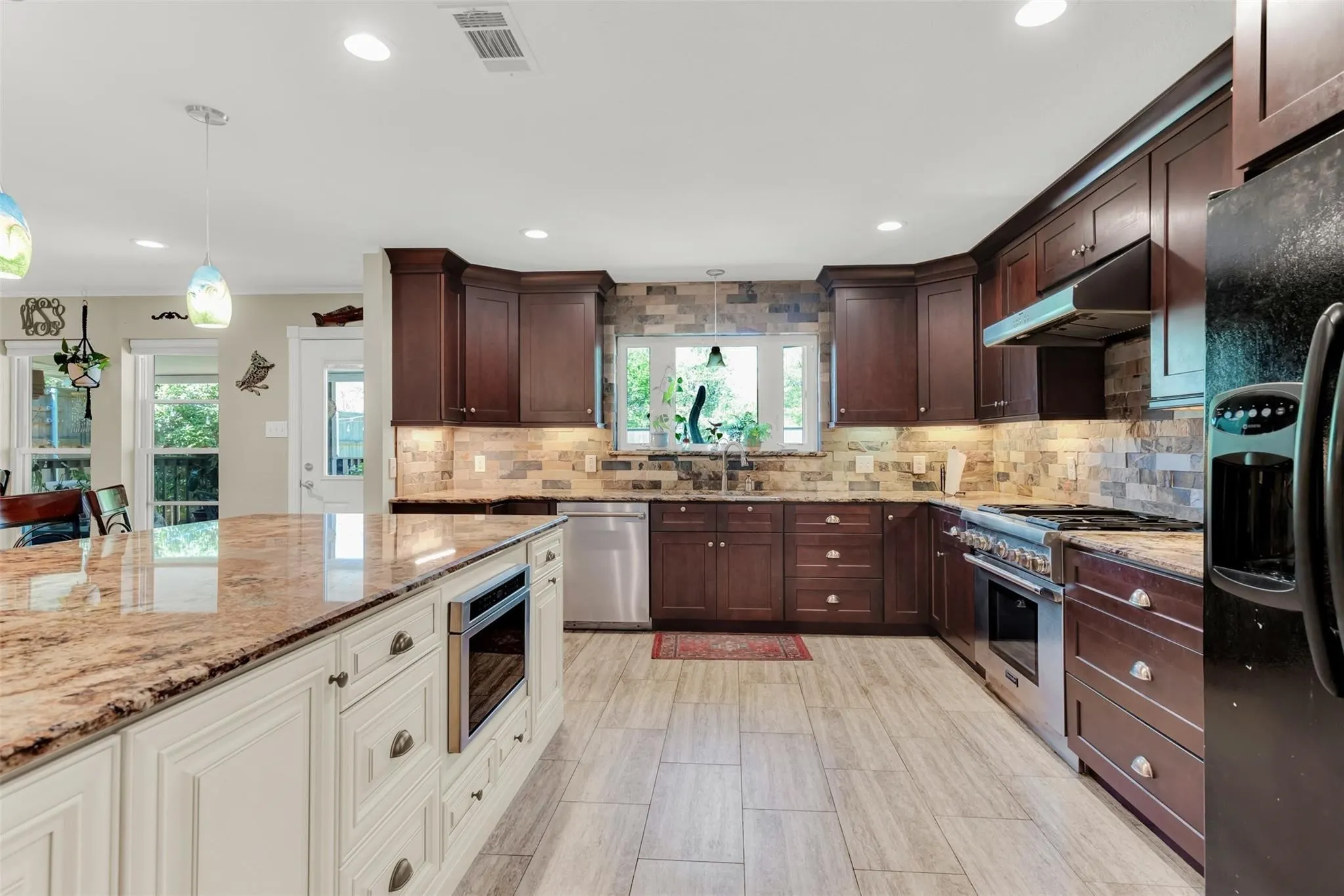 Gourmet kitchen featuring a large island with built-in microwave, wood-finish flooring, recessed lighting, stone backsplash, and dark wood cabinetry
