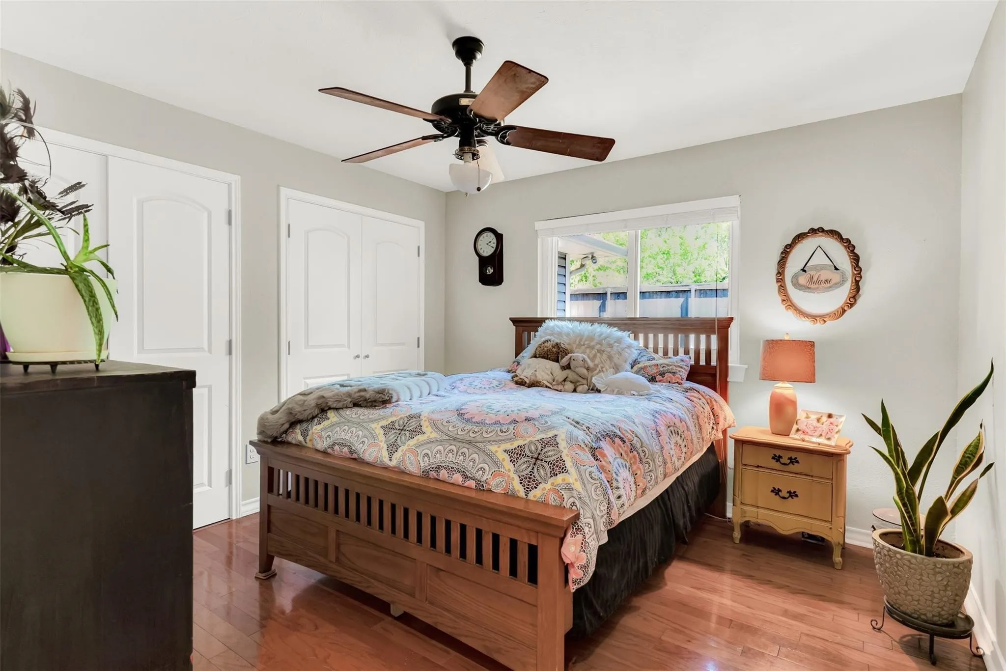 Wood-finish flooring, white walls, built-in ceiling fan with light, and a window with a white frame