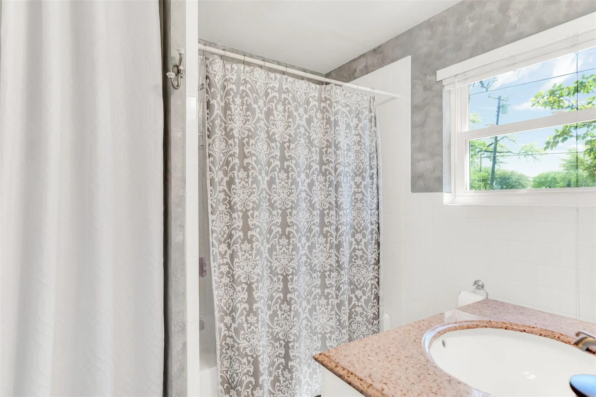 Bathroom featuring a window, white subway tile wainscoting, a vanity with an integrated sink, and a speckled countertop