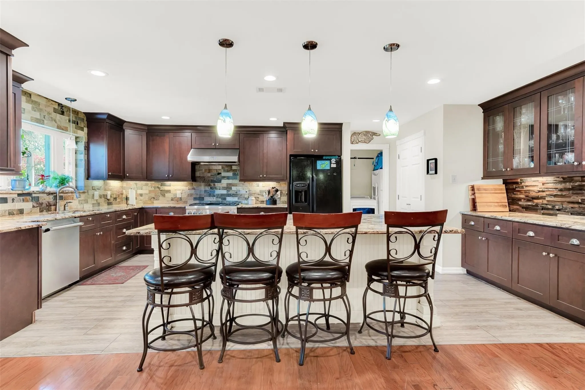 Kitchen featuring wood cabinetry, an island with seating, pendant lighting, and a tile backsplash