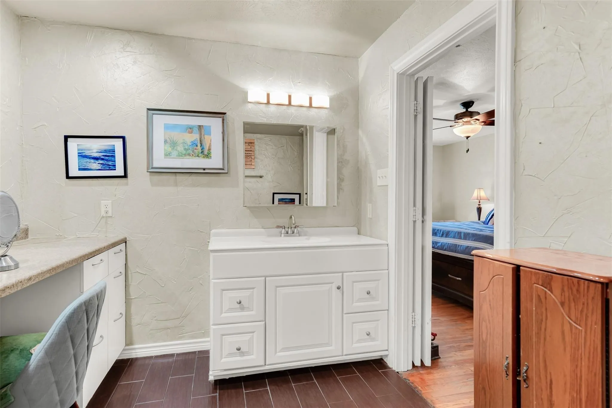 Vanity area featuring a white cabinet with a built-in sink, a wall-mounted mirror, and overhead strip lighting